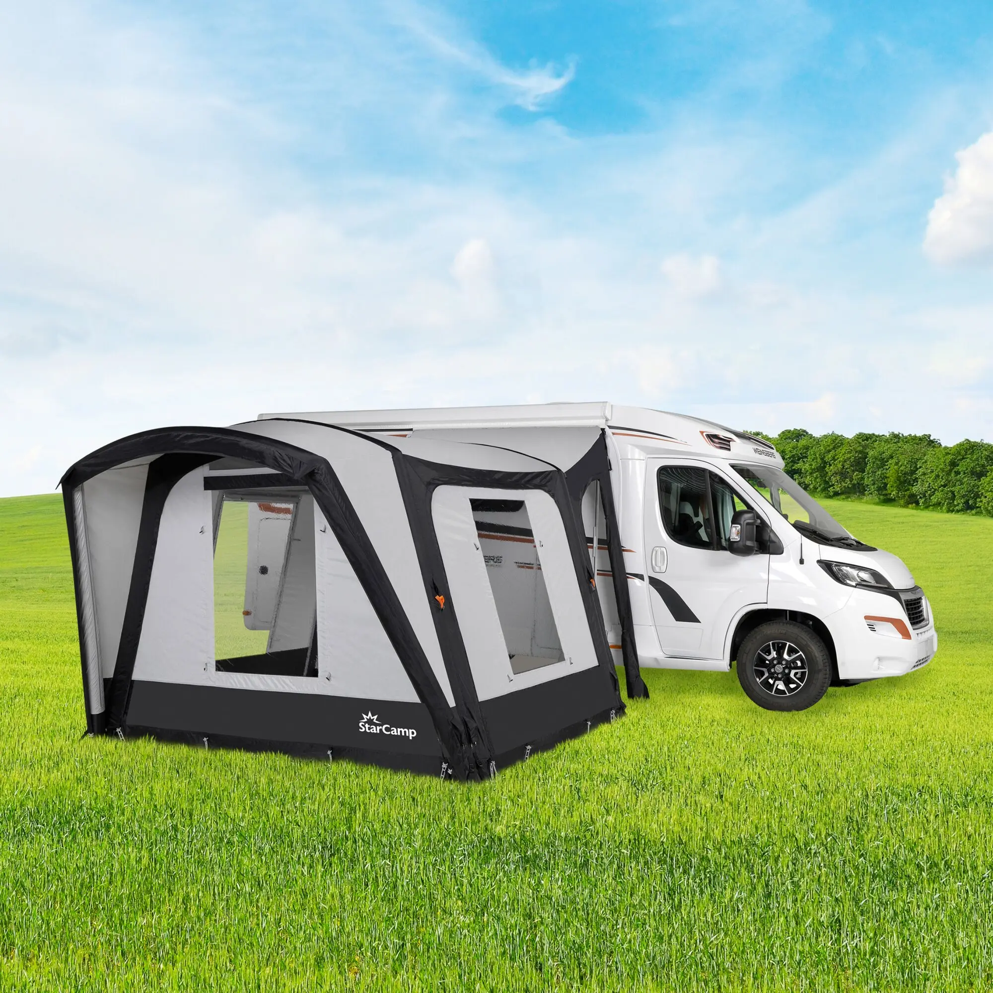 Weißes Wohnmobil mit seitlichem Anbauzelt in Grau, große Fenster, offener Eingangsbereich, StarCamp-Logo, grüne Wiese und blauer Himmel