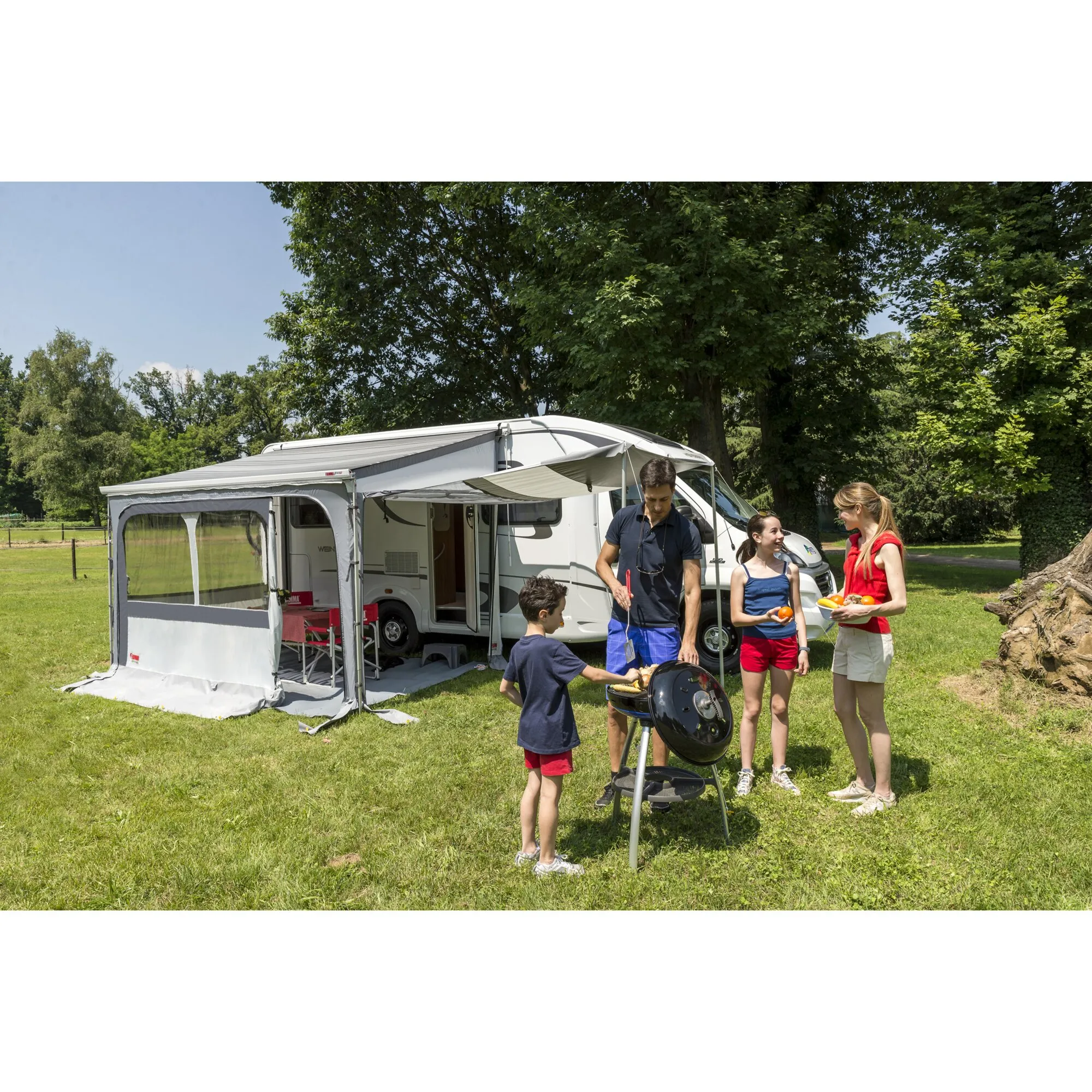 Graues Markisenzelt Privacy Ultra Light mit 450 cm Breite an einem Wohnmobil, davor eine Familie beim Grillen auf einer Wiese