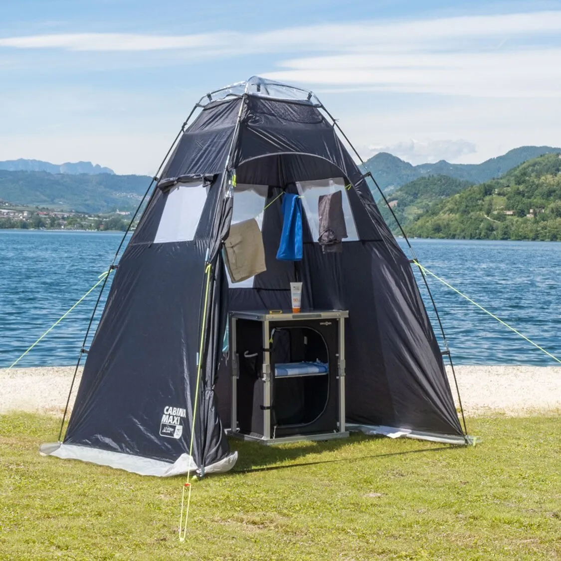 Schwarzes Strandzelt Cabina Maxi NG mit geöffnetem Eingang, Wäscheständer und See- sowie Berglandschaft im Hintergrund
