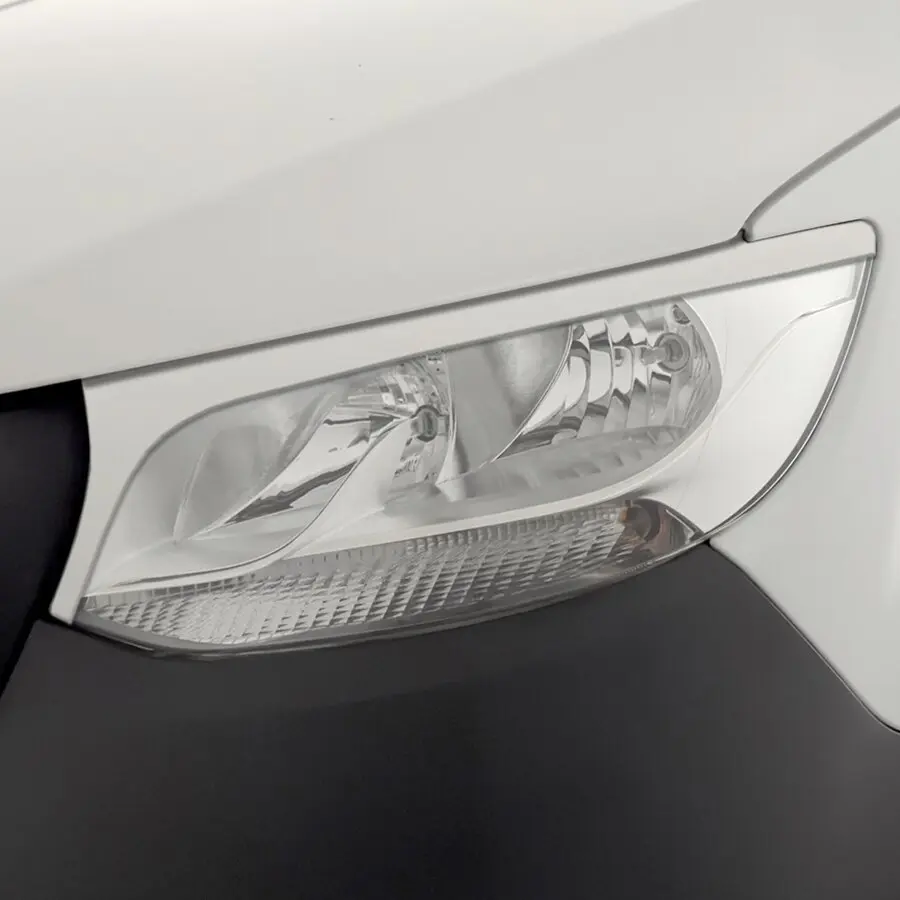 Nahaufnahme des vorderen linken Scheinwerfers eines weißen Mercedes-Benz Sprinter, klare Linse, dunkler Stoßfänger unten