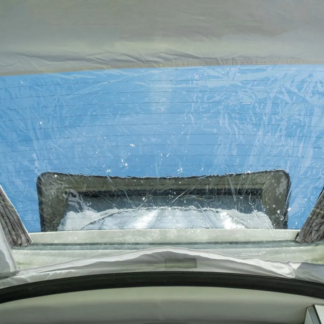 Innenansicht des Heckzelts Pilote Caddy 4 mit blauem, transparentem Außenmaterial und rechteckigem Fensterbereich am Fahrzeugheck