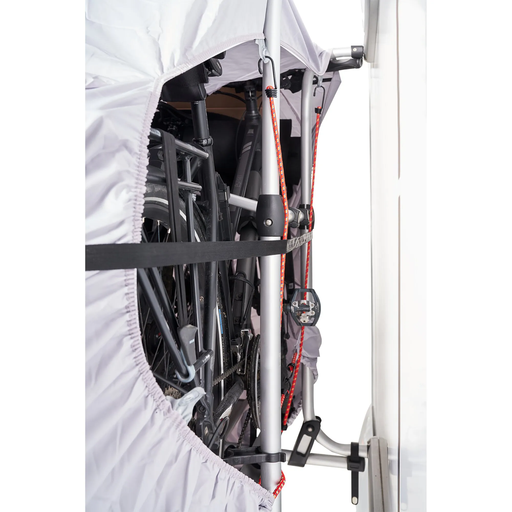 Weiße Fahrradschutzhülle mit elastischem Rand schützt mehrere Fahrräder auf einem Heckträger am Fahrzeug
