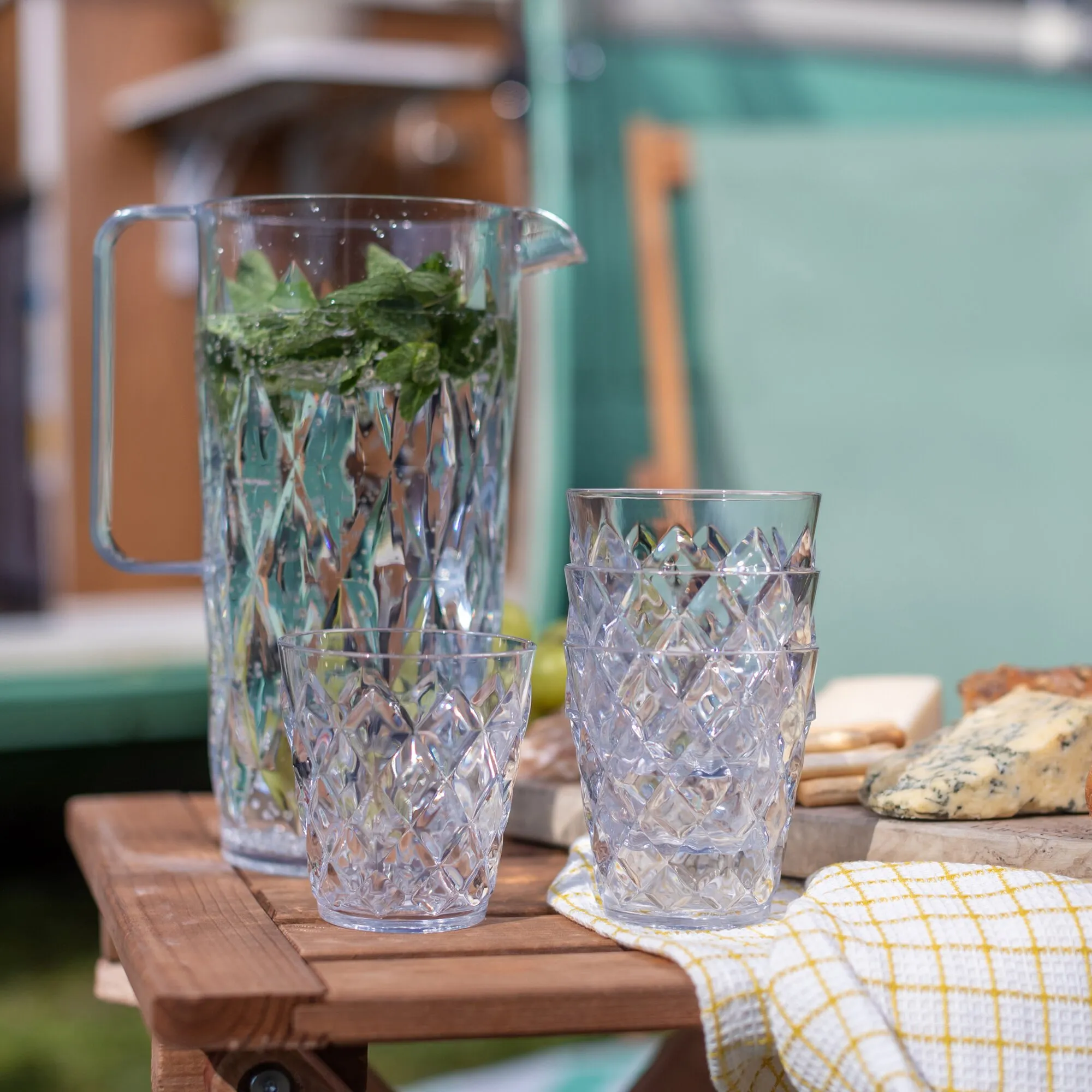 Kanne CRYSTAL aus transparentem Glas mit geometrischem Muster, Minzwasser und zwei sichtbaren passenden Bechern auf einem Holztisch