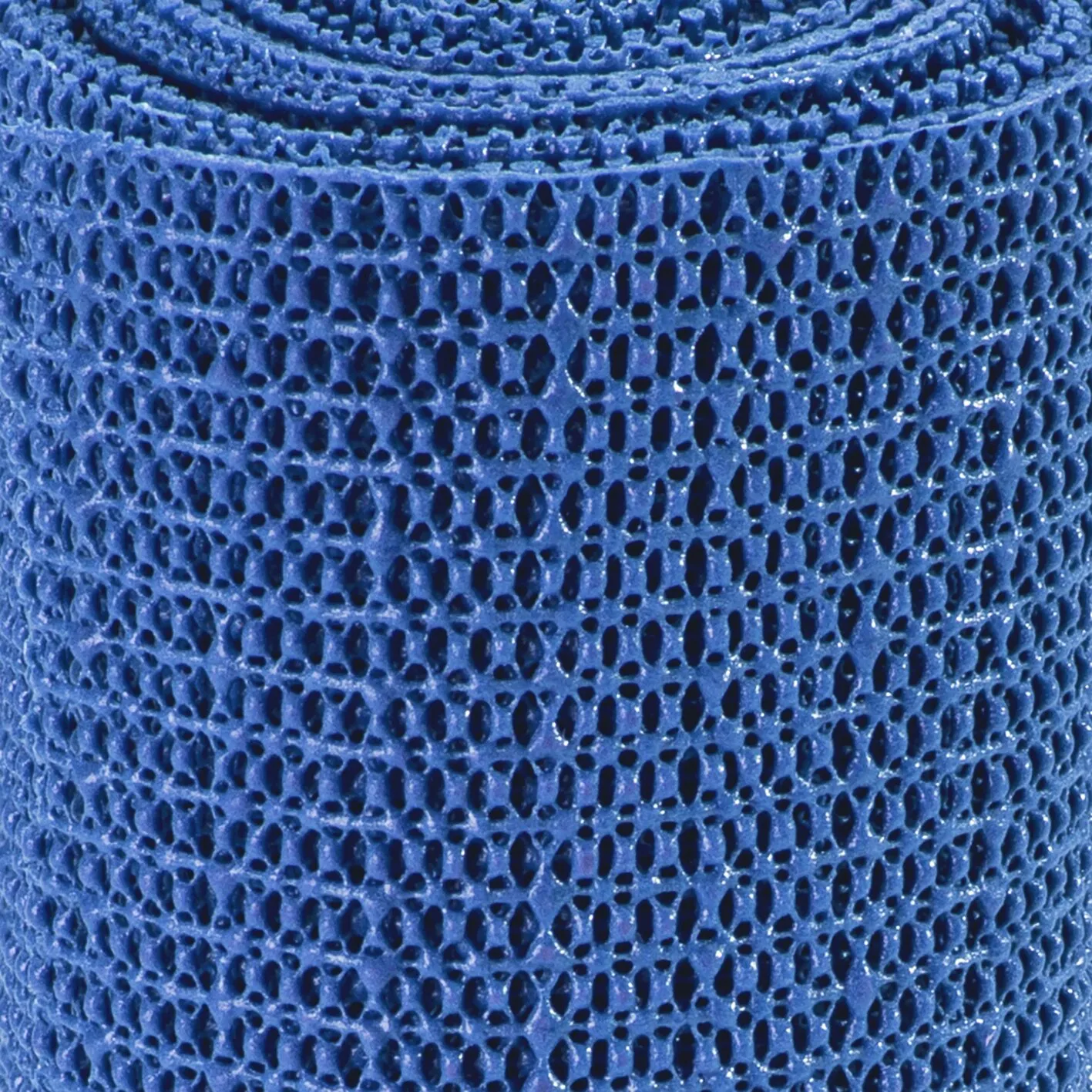 Detailaufnahme einer blauen Antirutschmatte mit dichtem, unregelmäßig perforiertem Wabenmuster