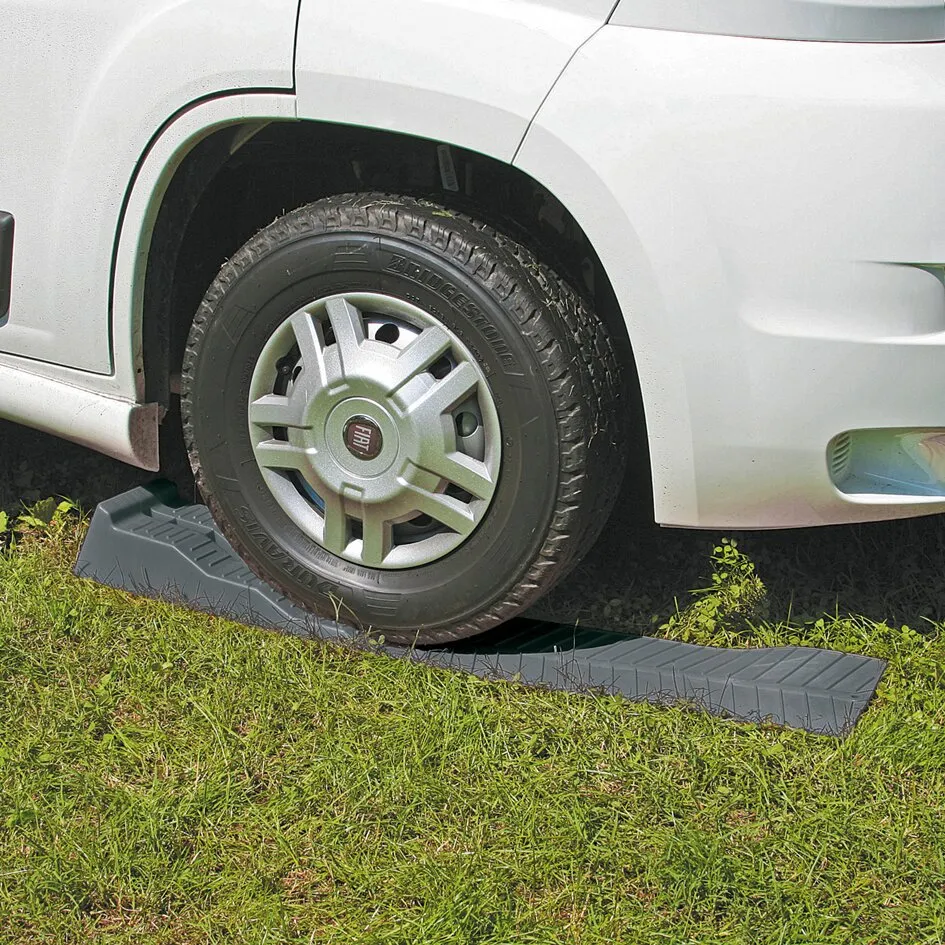 Grauer Auffahrkeil Level Up unter dem Vorderrad eines weißen Fiat-Transporters auf einer Wiese