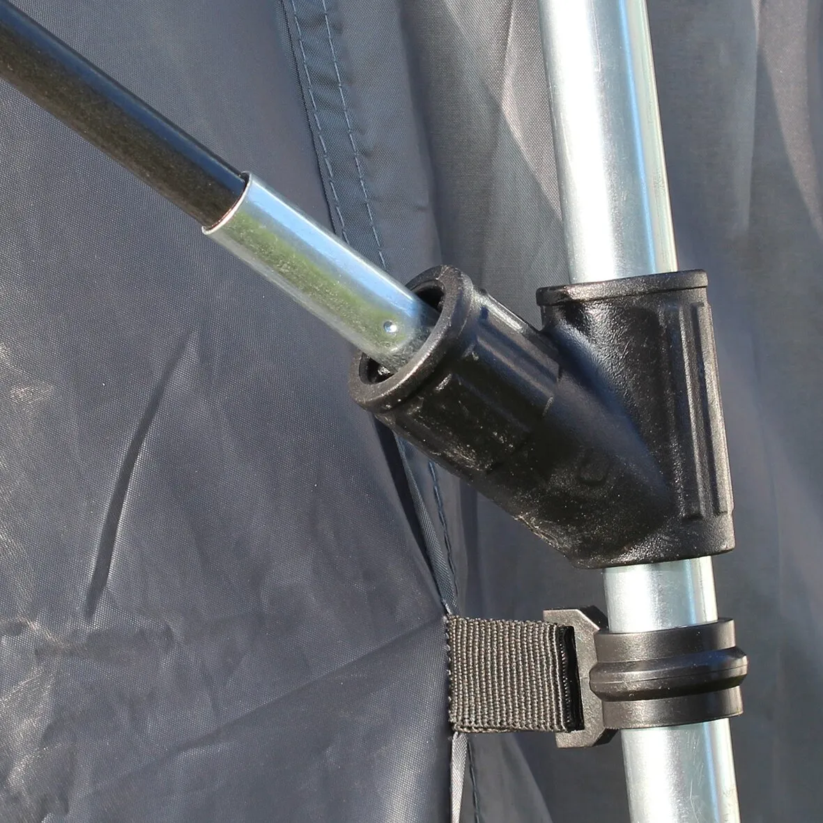 Detailaufnahme des Busvorzelts Pisa mit silbernen Aluminiumstangen, schwarzem Kunststoffgelenk und befestigtem Gurt an dunkelgrauem Zeltstoff