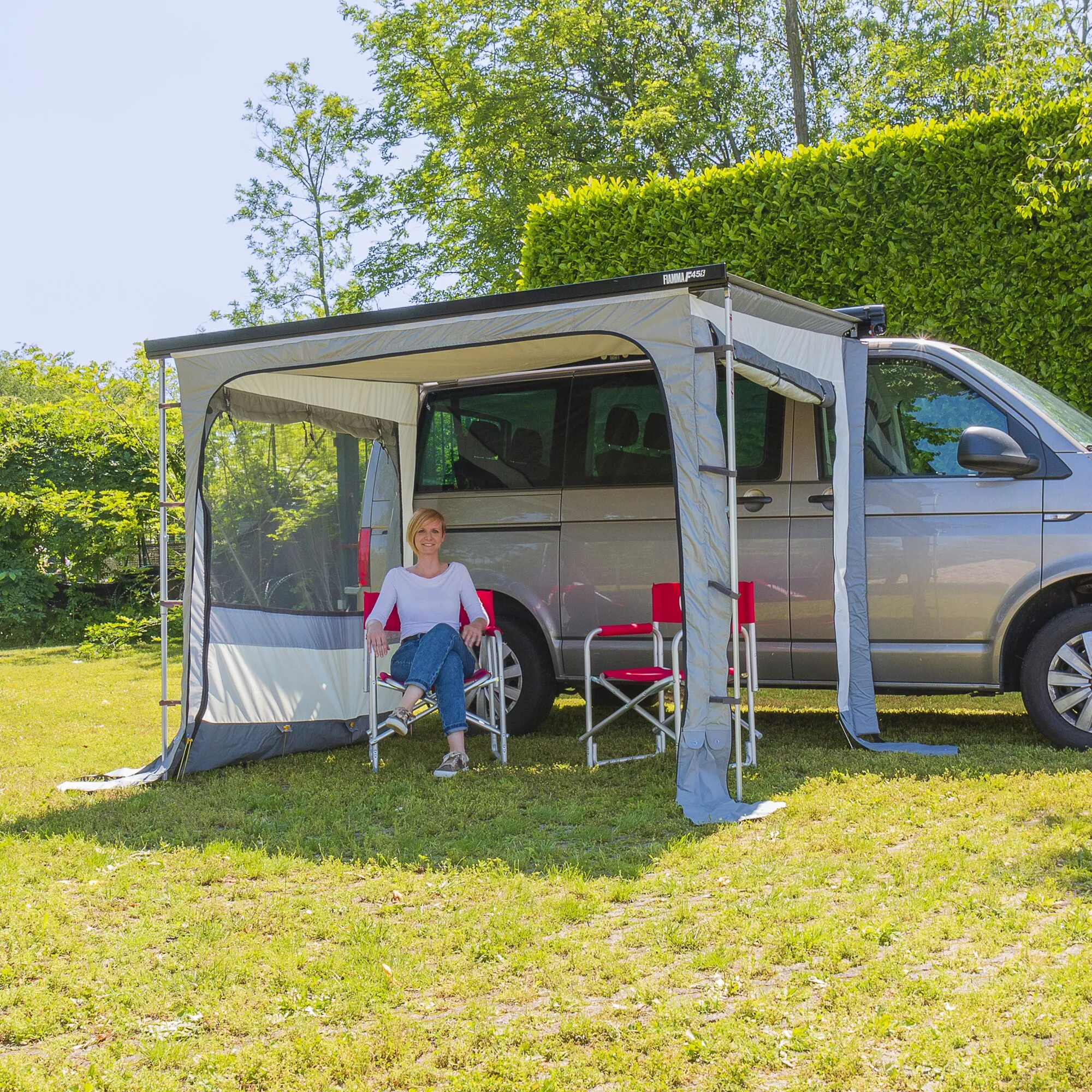 Graues Markisenzelt Privacy Ultra Light mit 450 cm Breite am Wohnmobil, eine Frau sitzt darin auf einem Campingstuhl