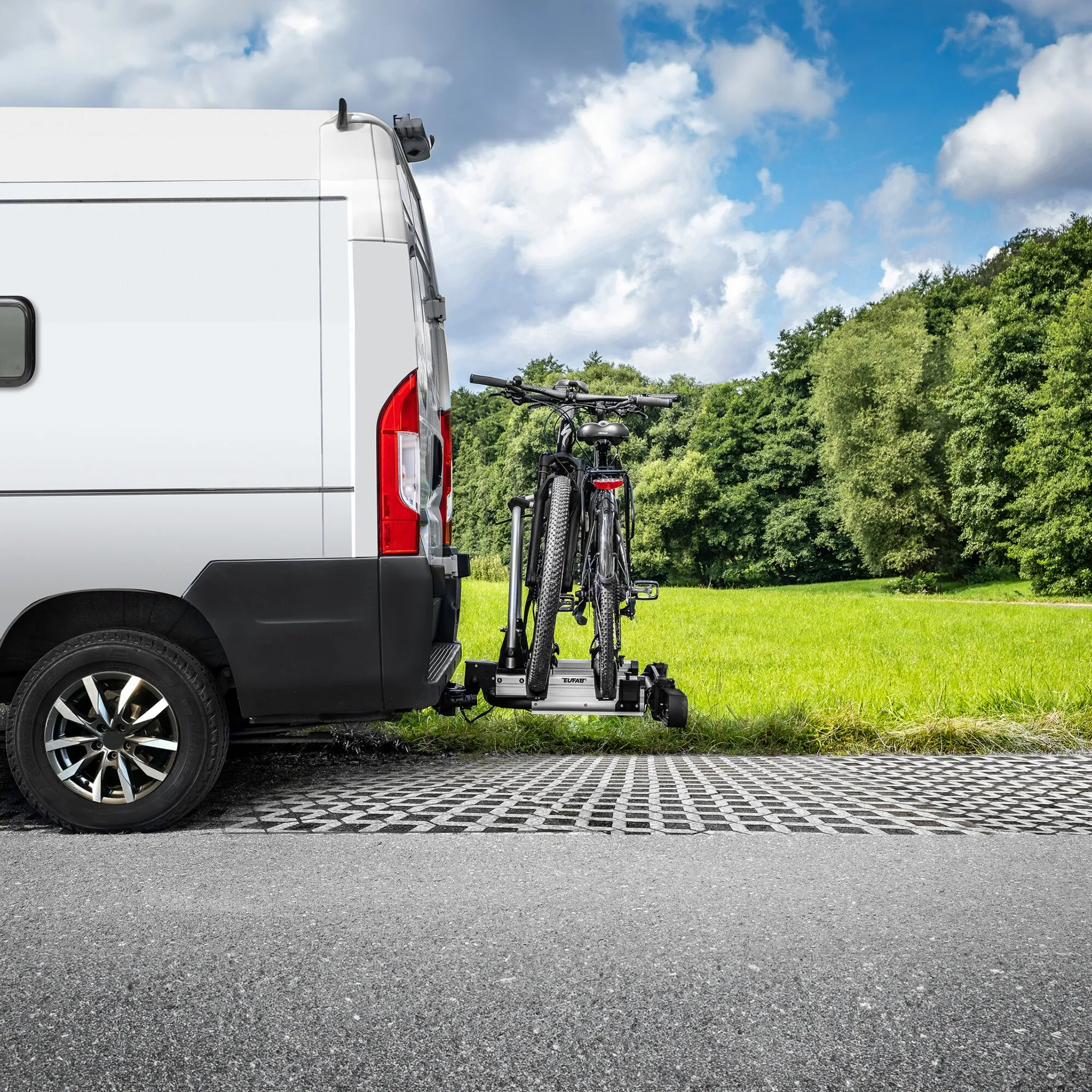 Silberner Fahrradträger SD260 an der Anhängerkupplung eines Wohnmobils, beladen mit zwei Fahrrädern auf einer Wiese