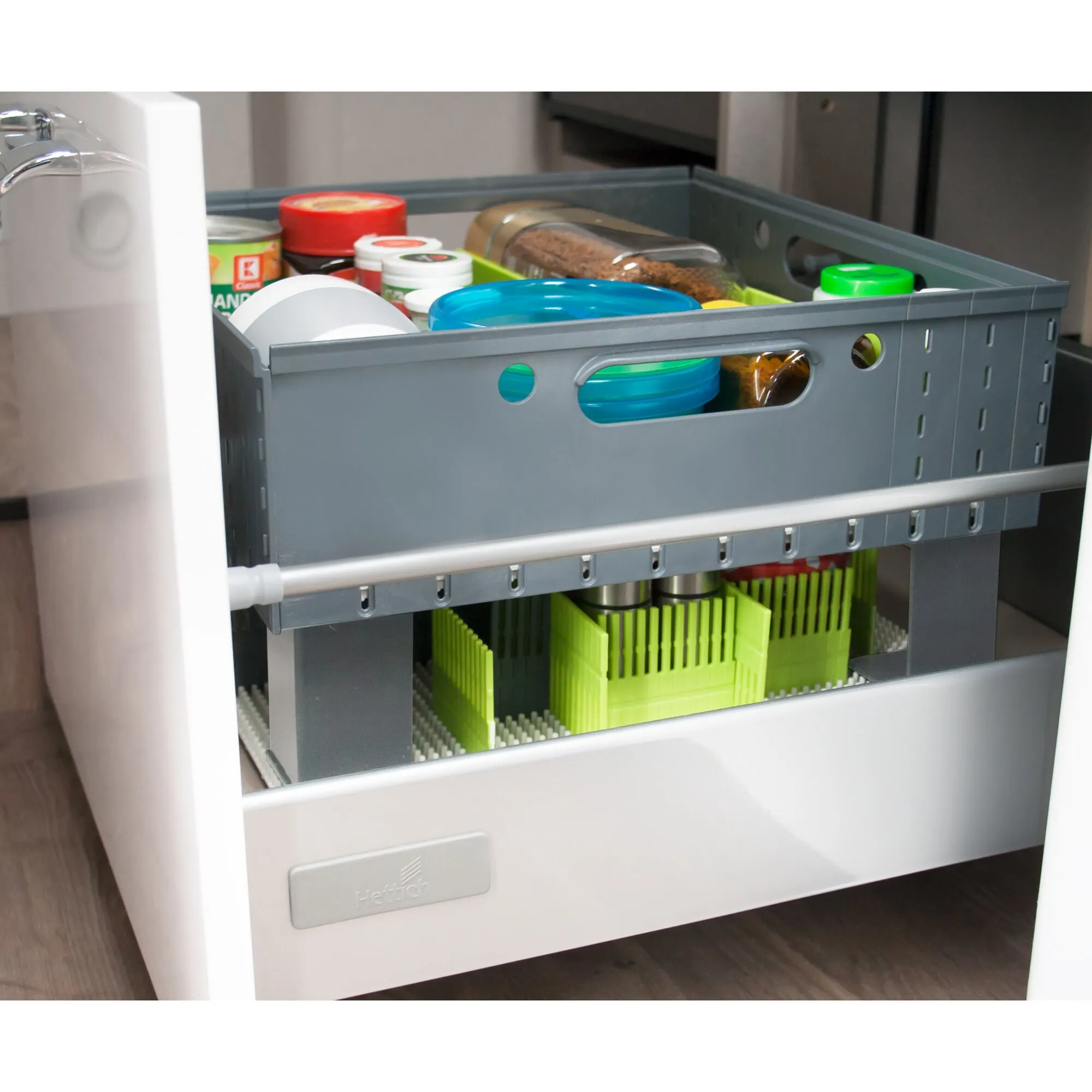 Graue Staubox mit Tragegriffen, gefüllt mit Vorräten und auf einer ausziehbaren Schublade im Küchenschrank verstaut