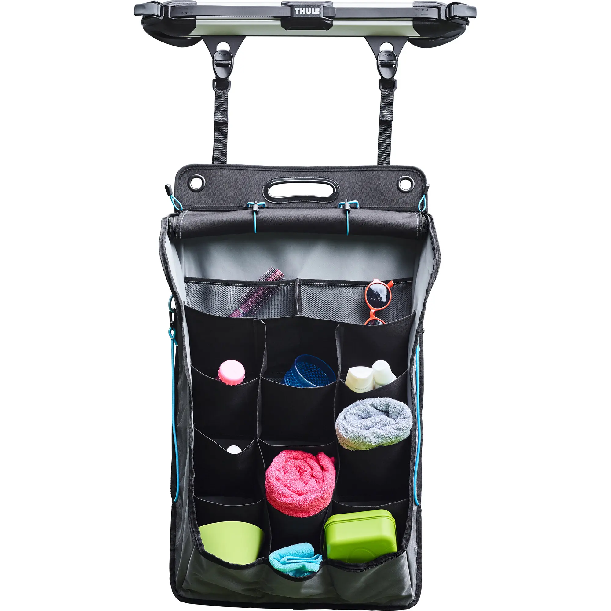 Magnetbefestigungsset mit zwei schwarzen Gurten, oben montiert, hält eine Organizer-Tasche mit Fächern, darin Sonnenbrille, Flaschen und Handtücher
