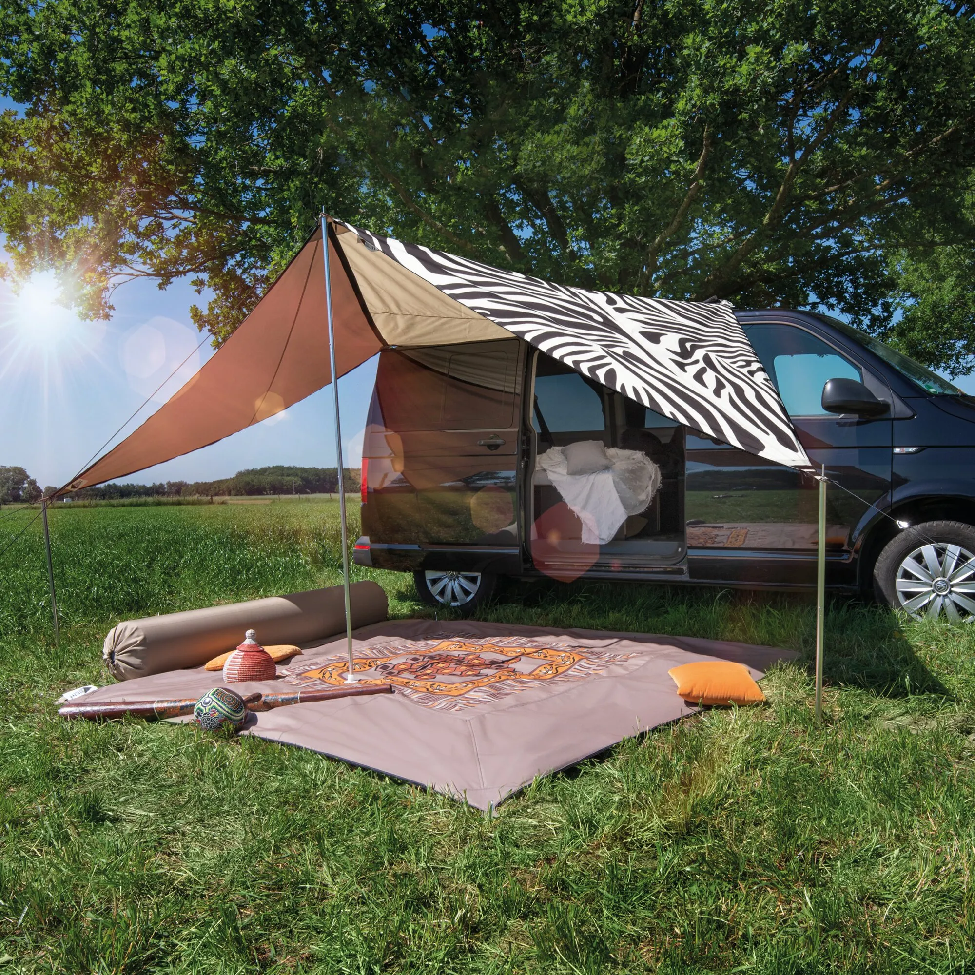 Sonnensegel TC-Zip Canvas Africa Nomad mit Zebra-Muster am geöffneten Campingbus auf einer Wiese aufgespannt
