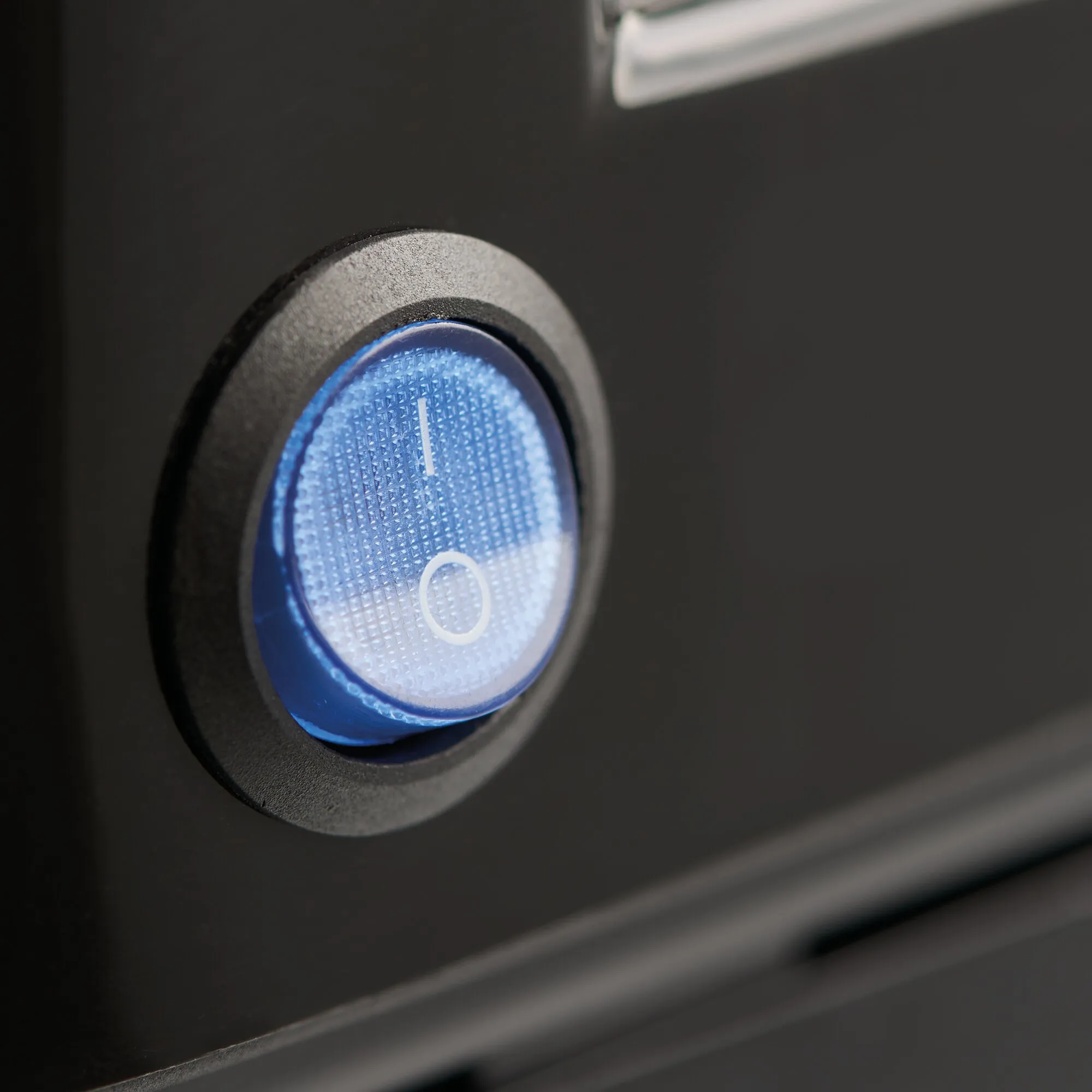 Detailaufnahme der schwarzen Kaffeemaschine Perfect Coffee mit blau beleuchtetem, rundem Ein-/Ausschalter