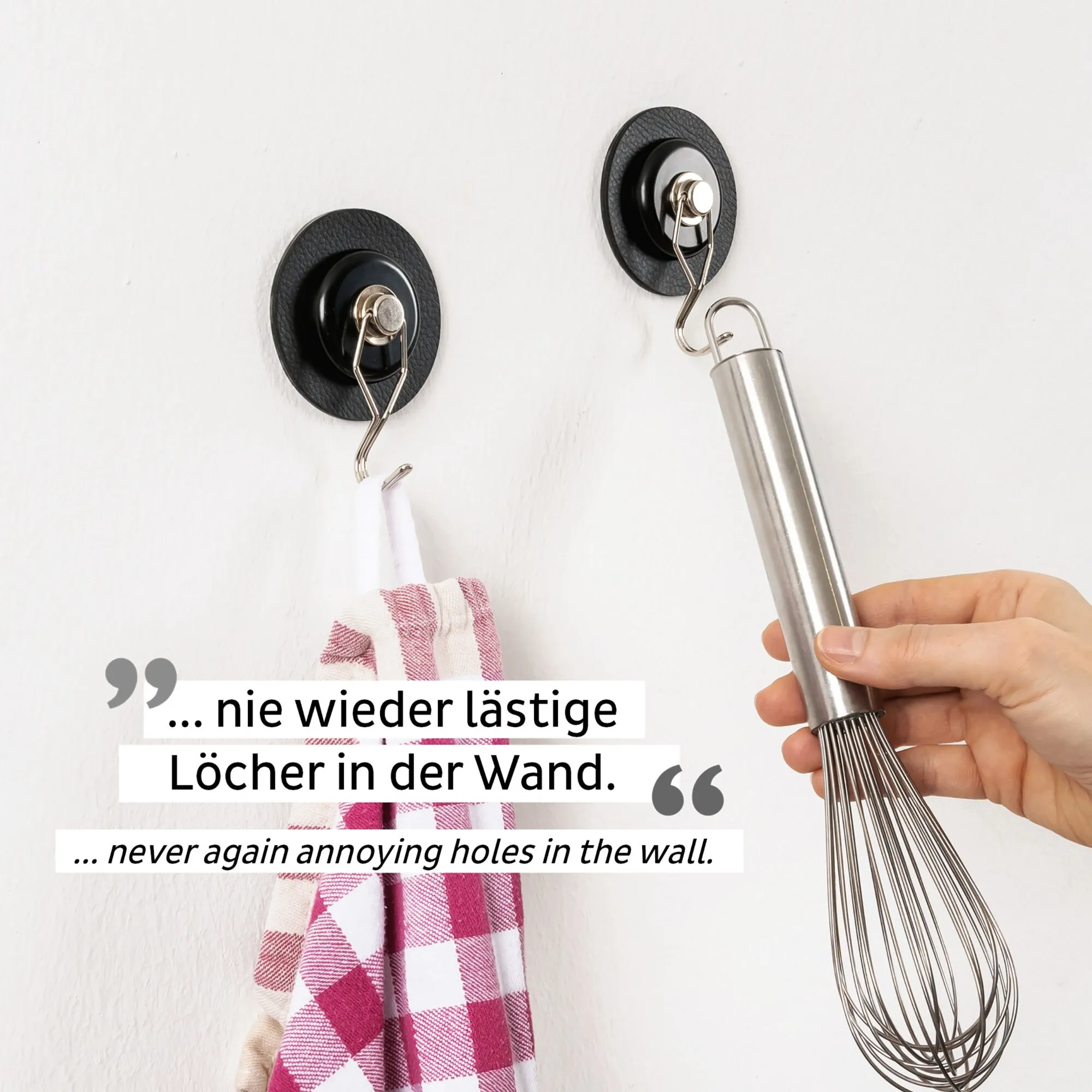 Zwei schwarze Magnet-Haken an einer weißen Wand, einer mit Geschirrtuch, der andere mit Schneebesen; Text weist auf bohrfreie Befestigung hin