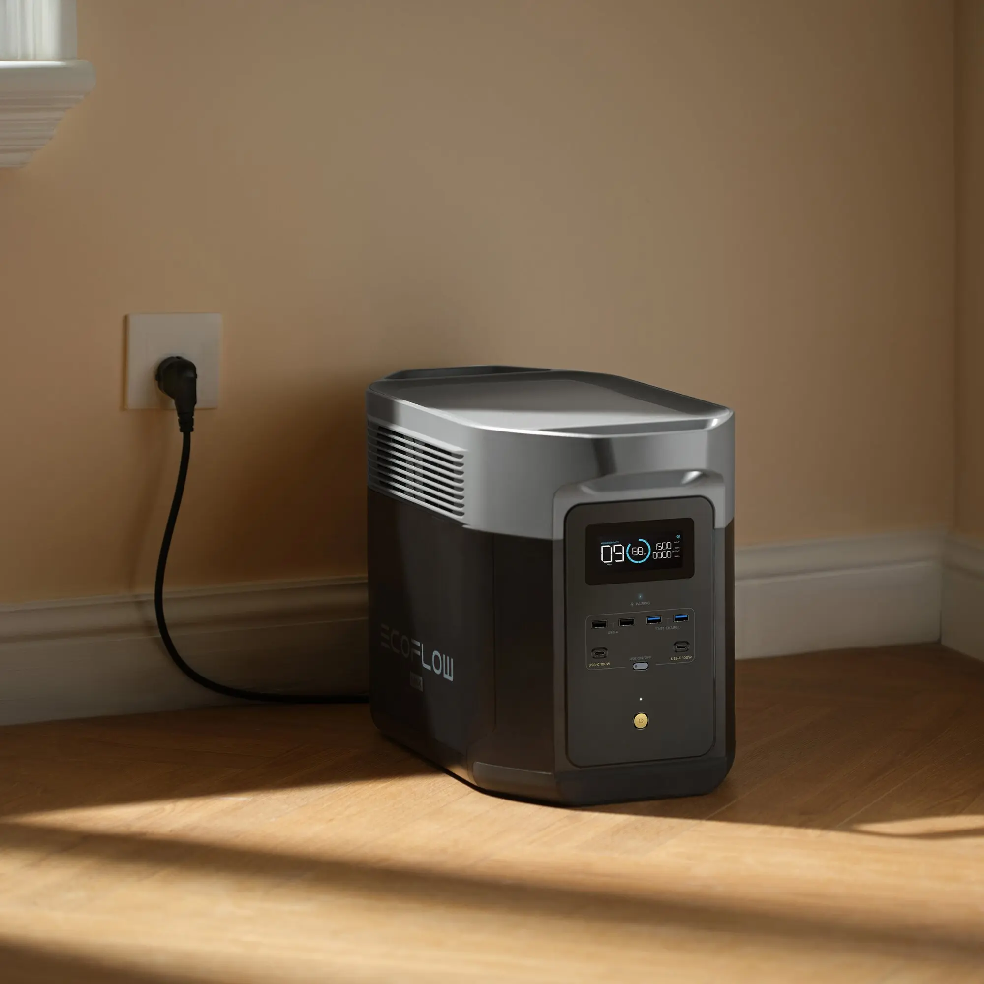 Graue EcoFlow Delta 2 Max Powerstation mit Frontdisplay und Lüftungsschlitzen steht auf Holzboden neben einer Wandsteckdose