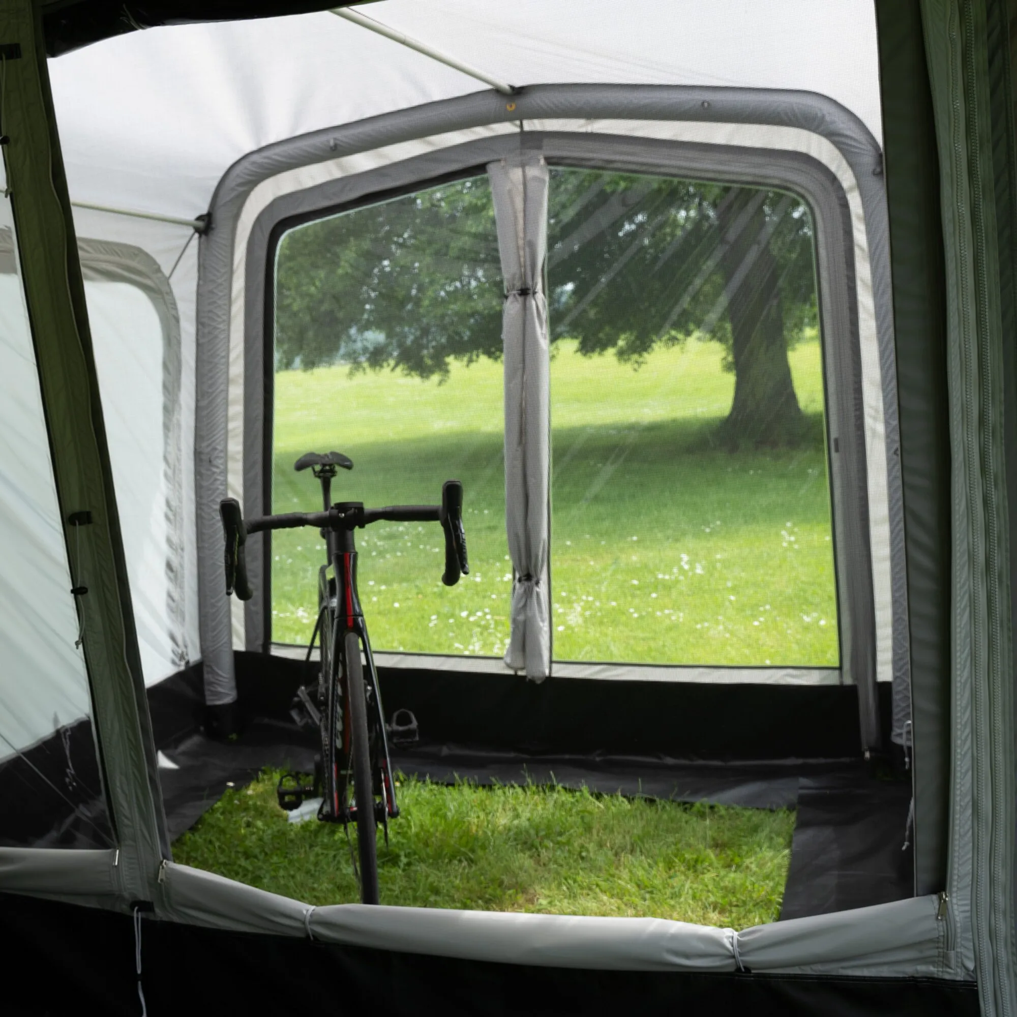Innenansicht des grünen Anbaus Eris für Vorzelte mit großem Moskitonetzfenster und abgestelltem Fahrrad