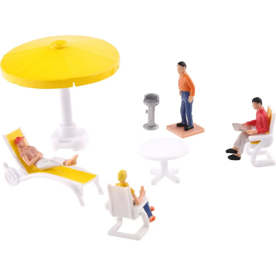 Miniatur-Campingzubehör mit gelbem Sonnenschirm, Liegestuhl, Tischen, Grill und drei sitzenden sowie einer stehenden Figur