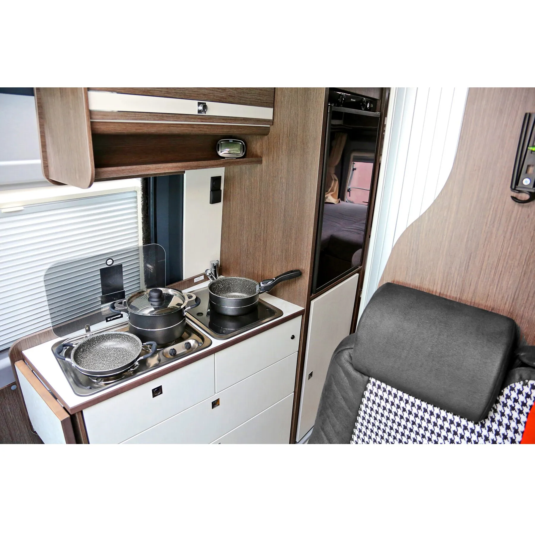 Topfset Pirate 7 + 1 mit schwarzen Töpfen und Pfannen, darunter ein Topf mit Glasdeckel, auf dem Herd eines Wohnmobils