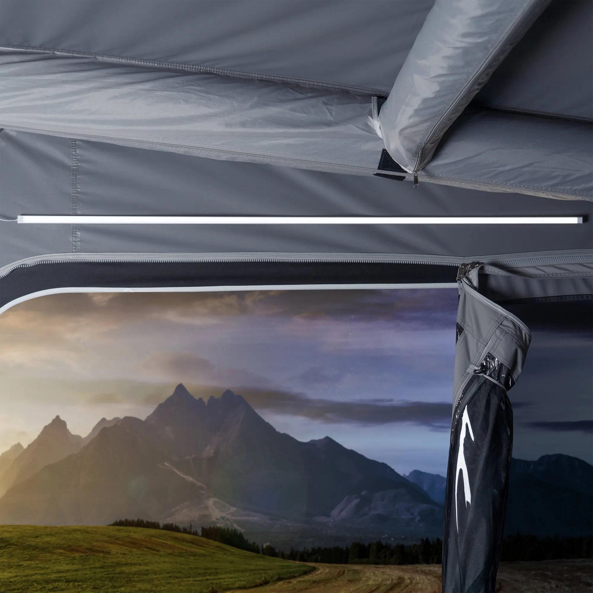 Weiße LED-Lichtleiste des Vorzelt-Sets an der Innenwand eines grauen Vorzelts mit Berglandschaft im Hintergrund