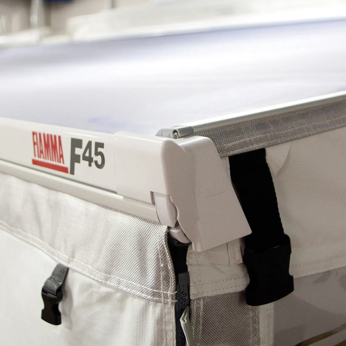 Weiße Rahmeneinheit eines F45-Trainingsgeräts mit grauer Gummiabdeckung Rain Caps an der Verbindung, daneben eine Stofftasche mit Mesh-Einsätzen