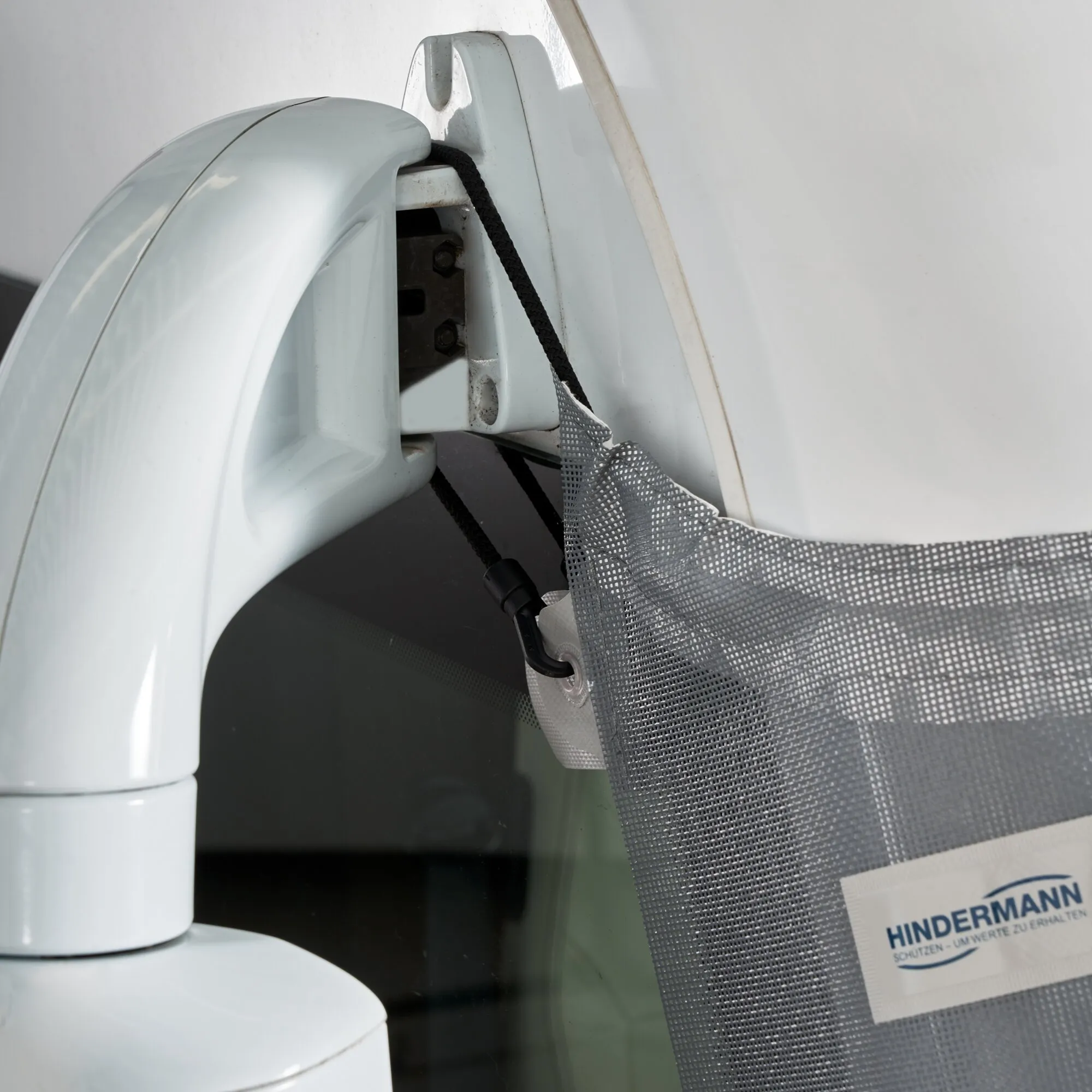 Detailaufnahme der grauen Sonnenschutzmatte Screen am integrierten Reisemobil, befestigt mit elastischer Kordel und Haken