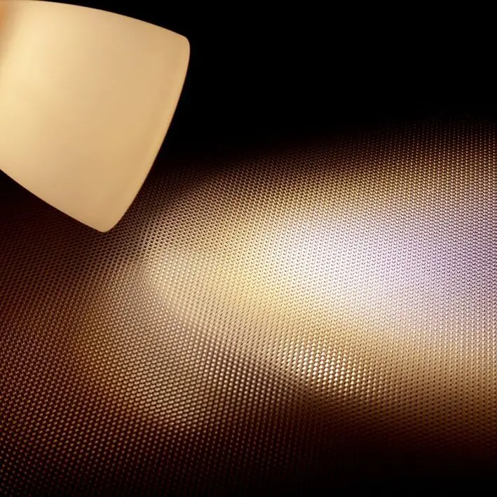 Aufbau-Leseleuchte aus Echtglas, warmweißes Licht 3000 K strahlt von links oben auf eine feine Punktraster-Oberfläche mit Glanz- und Schattenmustern