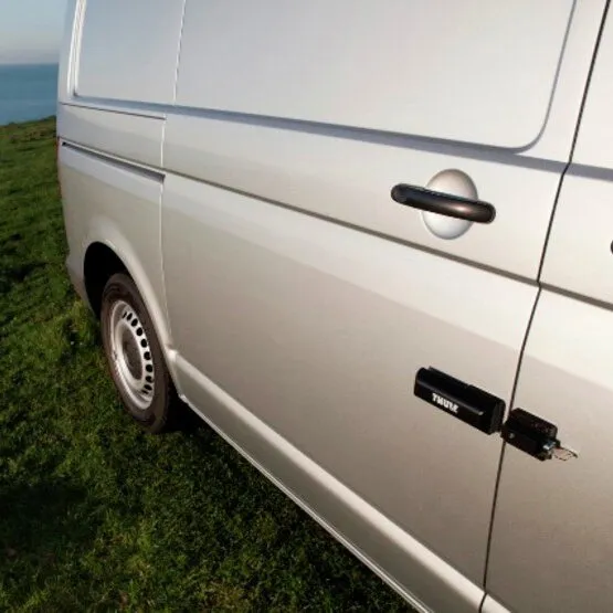 Weiße Van-Seitentür mit schwarzem Thule Van Lock und sichtbarem Verriegelungsbügel an der Türfuge