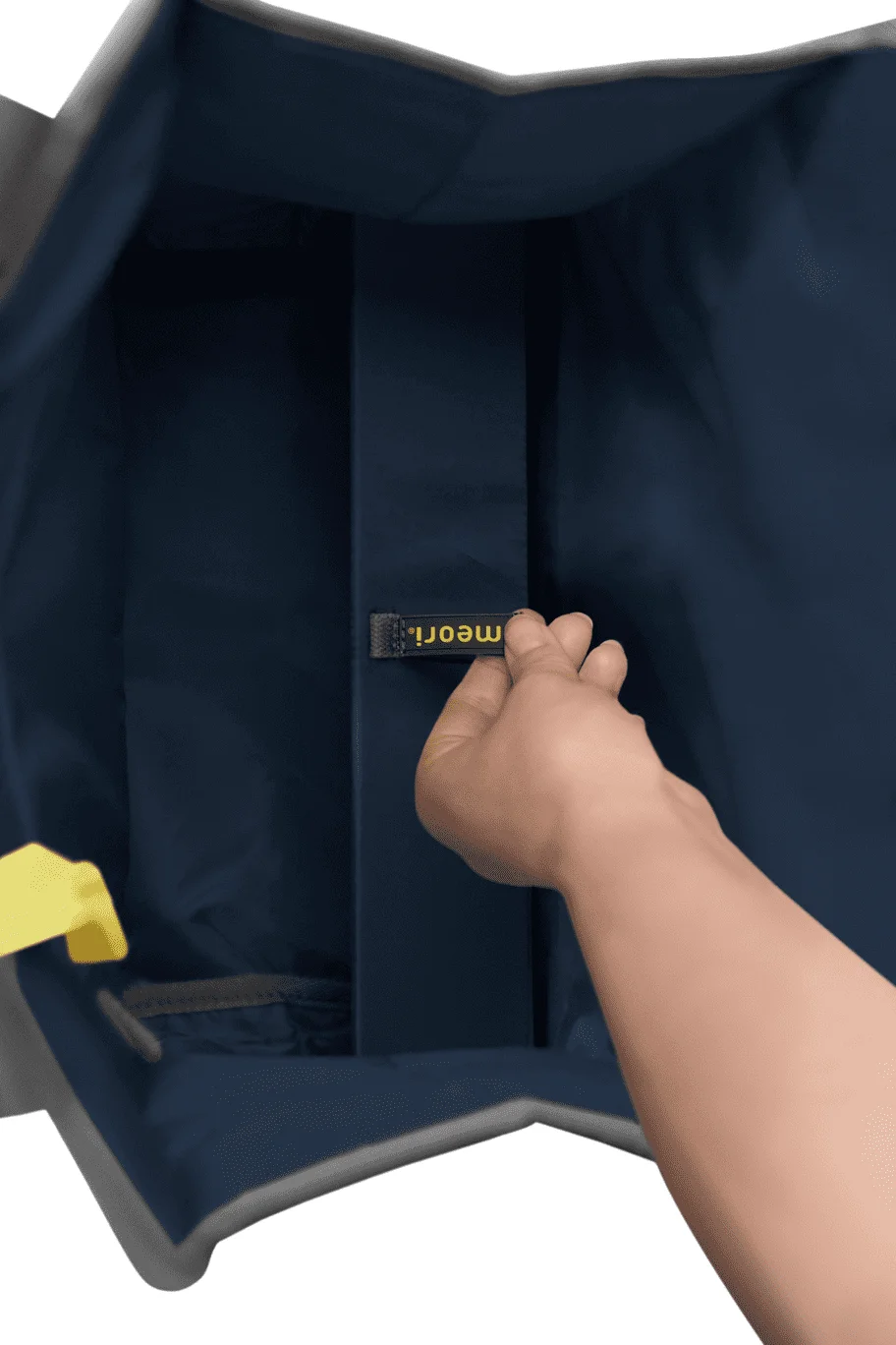Innenansicht einer dunkelblauen faltbaren Einkaufstasche, eine Hand greift nach einem kleinen Etikett mit gelber Aufschrift Meori