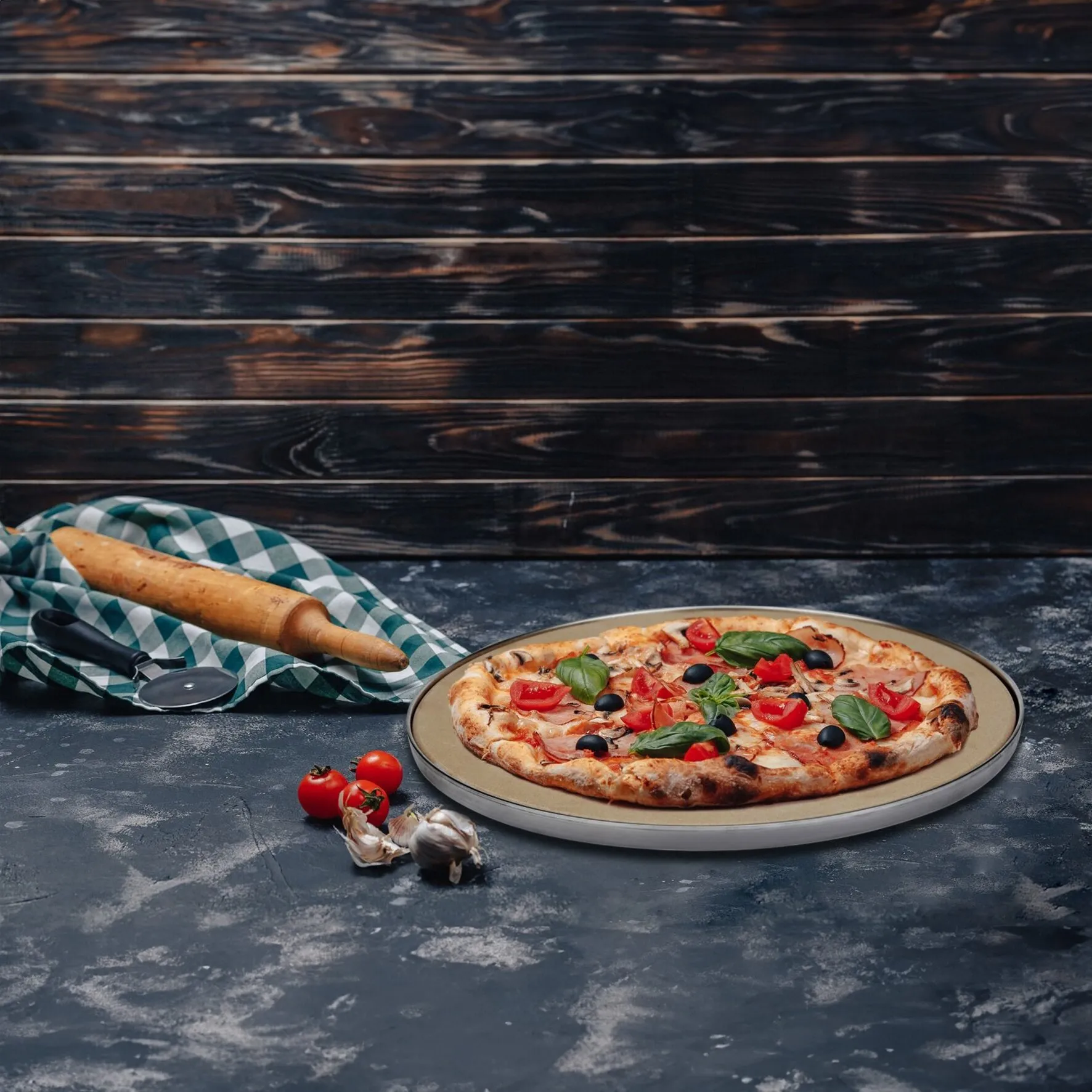 Runder Pizzastein Pro, 25 cm, mit belegter Pizza sowie Nudelholz und Pizzaschneider auf dunkler Arbeitsfläche