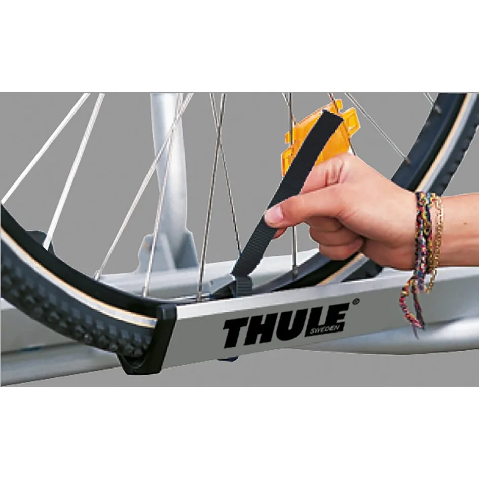 Schwarzes Nylon-Halteband wird am Fahrradreifen in einer Thule-Fahrradträger-Schiene befestigt