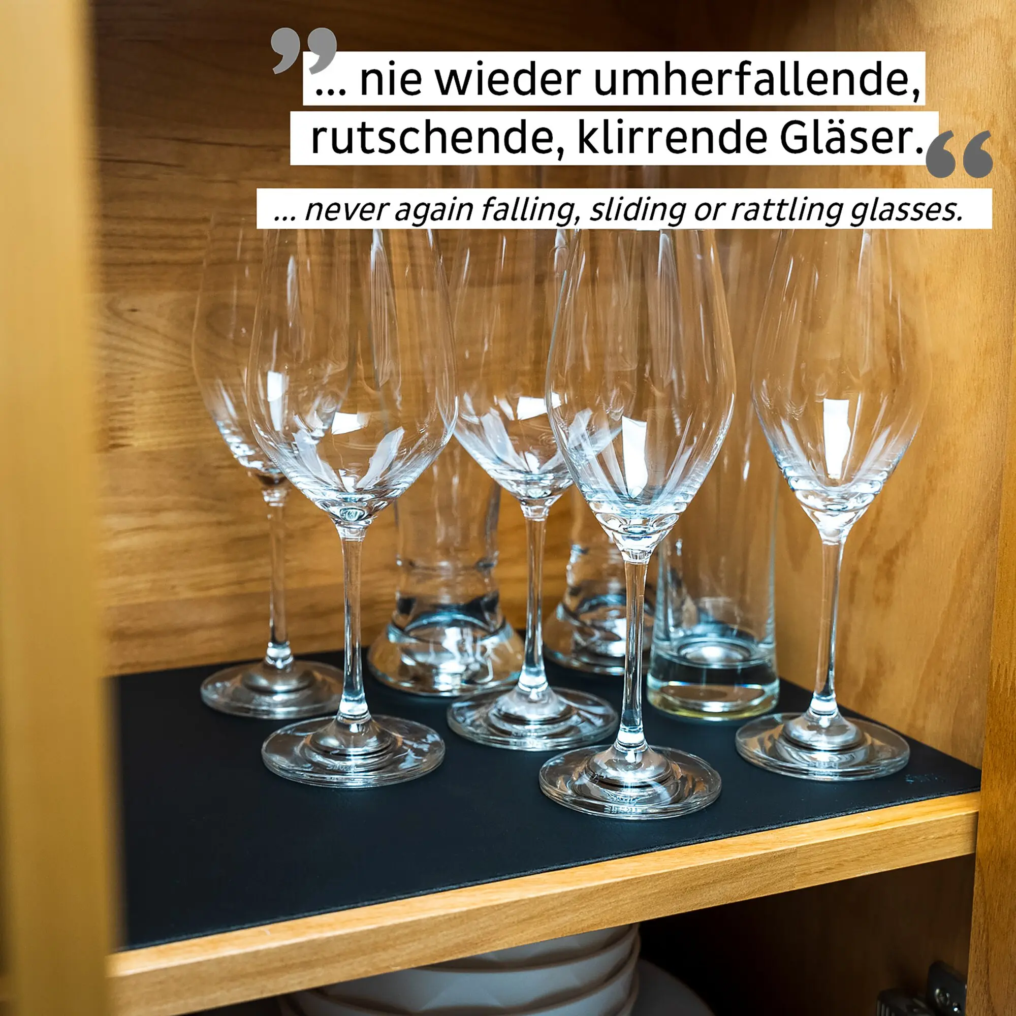 Mehrere Weingläser mit langen Stielen stehen auf einer schwarzen Matte in einem Holzkabinett, seitlich ist ein gelber Rahmen sichtbar
