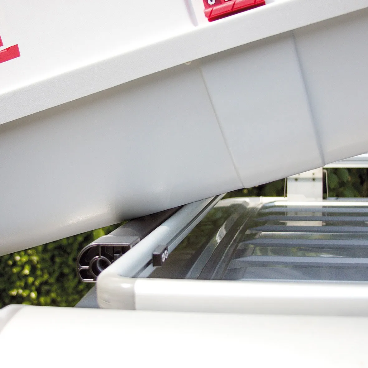 Detailaufnahme einer grauen Ladehilfe Roller Roof Rail an der Dachreling unter einer weißen Dachlast