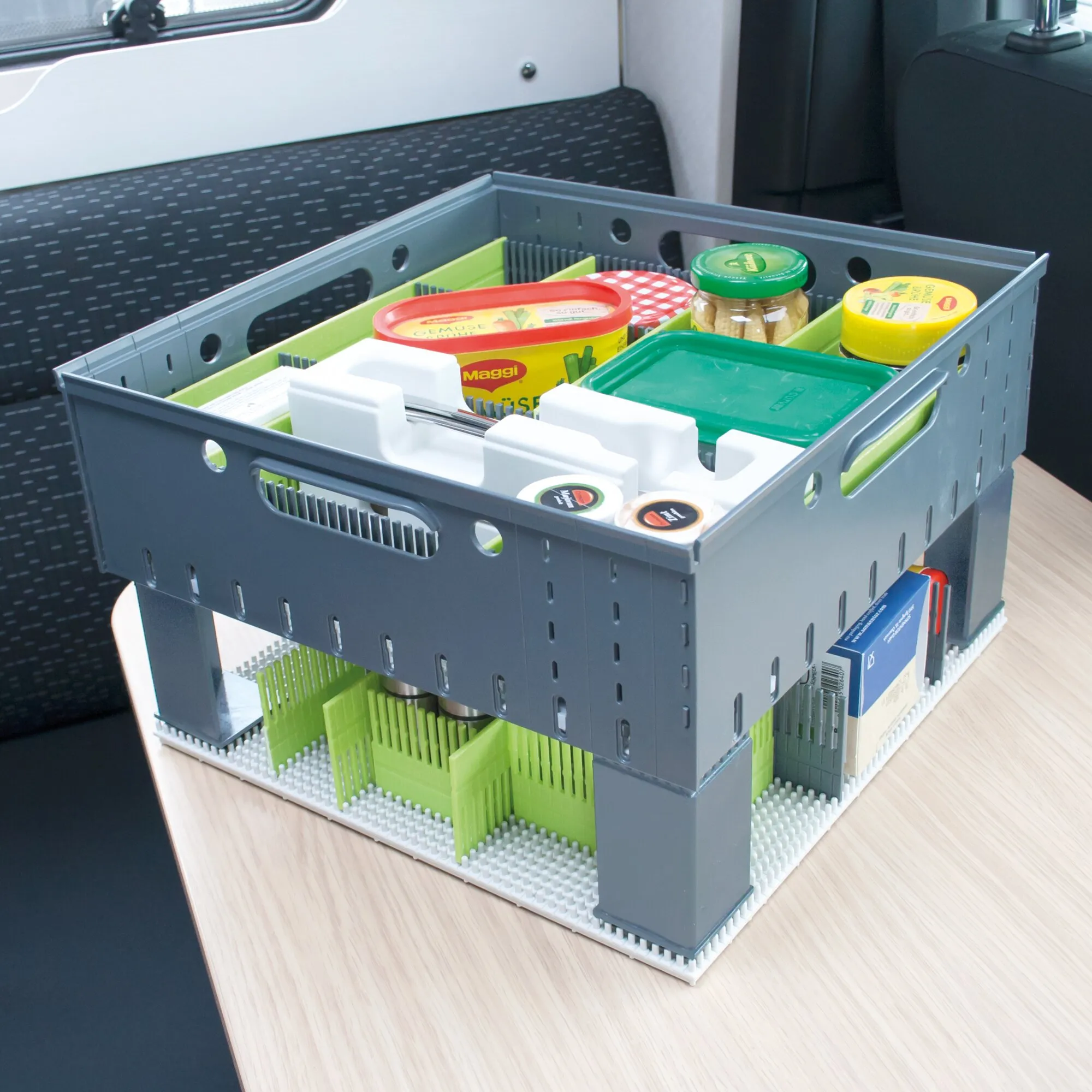 Graue Transportbox mit grünen Abstandshaltern ON-TOP, gefüllt mit Lebensmitteln und auf weiteren Boxen gestapelt