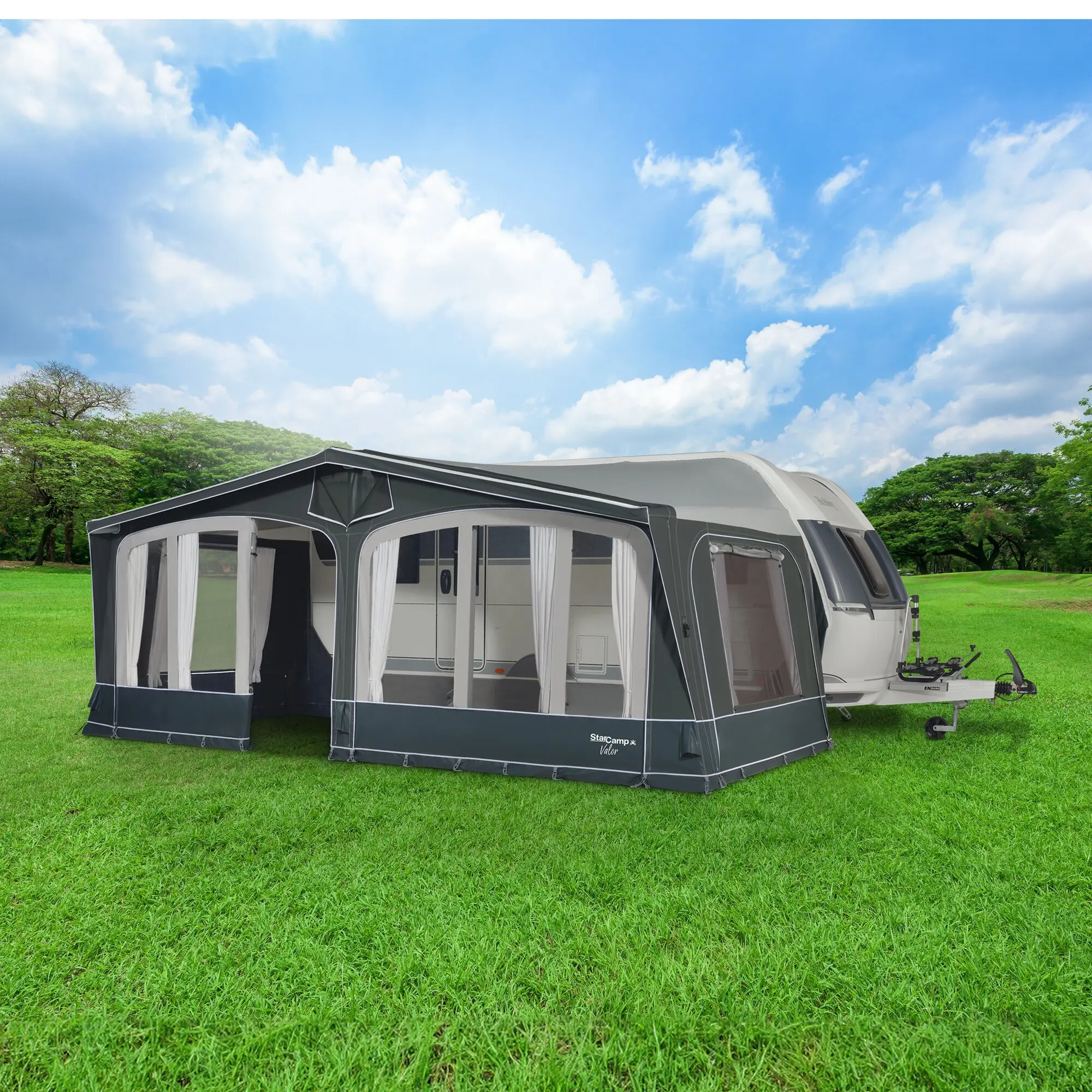 Valor Air Reisevorzelt 800 cm an einem Caravan, offene Seiten mit weißen Vorhängen, dunkelgrauer Zeltboden, grüne Wiese und blauer Himmel