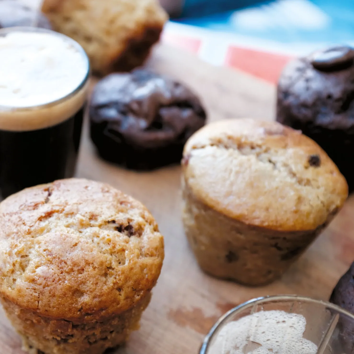 Verschiedene Muffins und Schokoladenküchlein neben Kaffee und einem Backbuch für Kuchen und Torten im Omnia Backofen