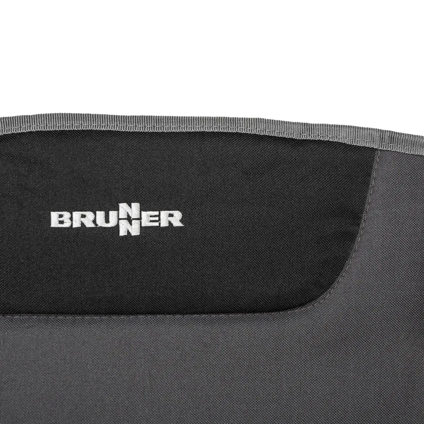 Nahaufnahme eines schwarzen Stoffmaterials mit dem weißen Brunner Logo, sichtbare Naht am oberen Rand und gewebte Textur