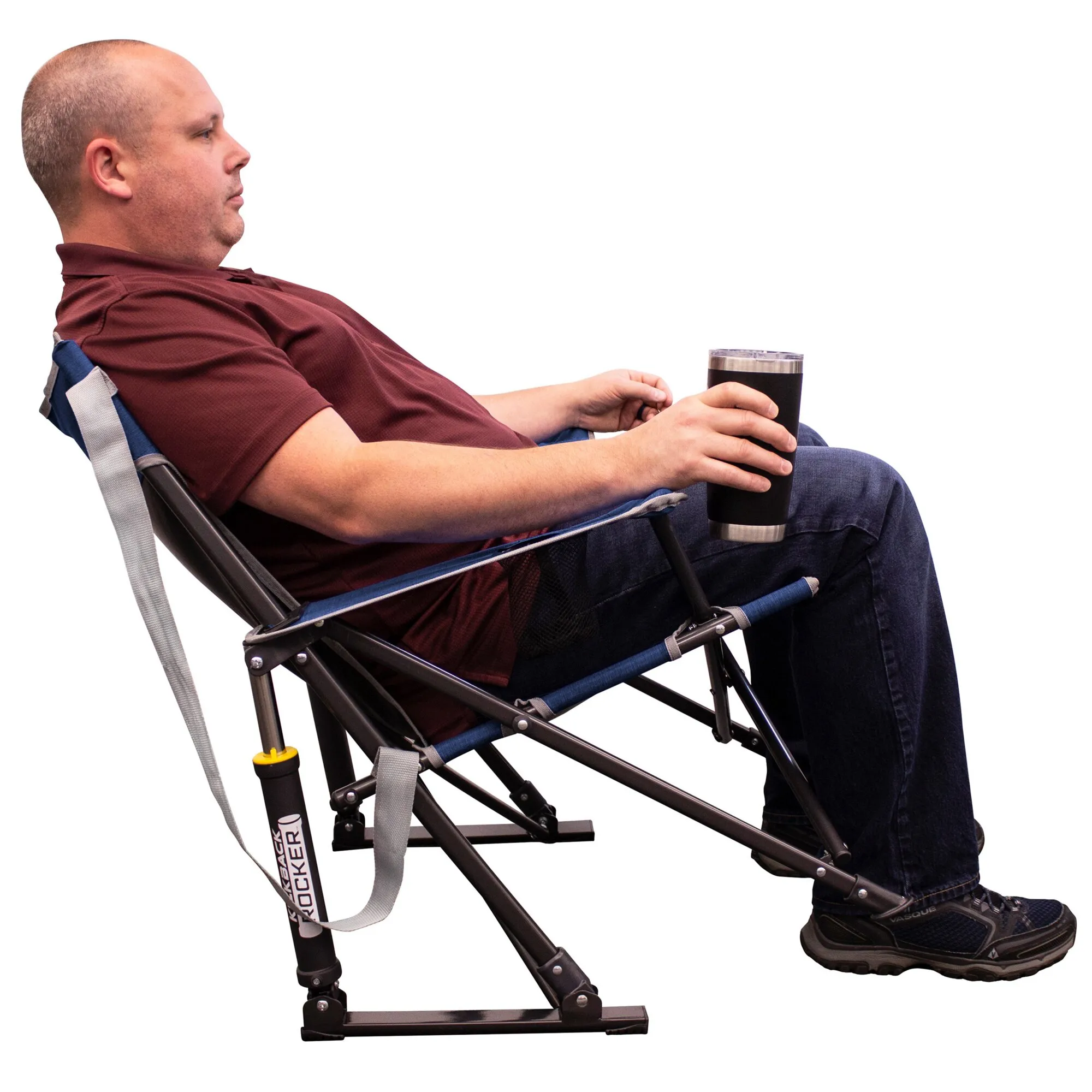 Mann sitzt in einem indigo-blauen Camping-Schaukelstuhl Kickback Rocker™ und hält einen schwarzen Thermobecher in der Hand