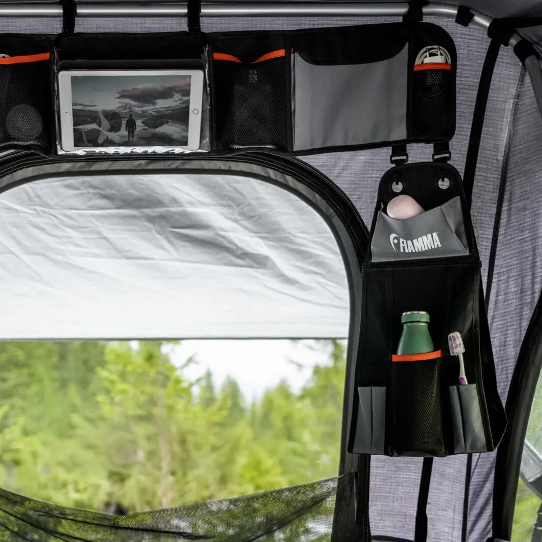 Innenansicht eines Zeltes mit Organizer Moonlight Tent Long; schwarze Fächer, Tablet im Transparentfach, rechts Ei im Fach, Flasche und Zahnbürste