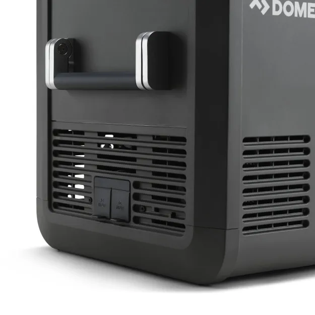 Nahaufnahme einer dunklen Kühlbox CFX5 55 mit Tragegriff, belüftetem Frontgitter und zwei Bedienknöpfen; Dometic-Logo am rechten Rand sichtbar