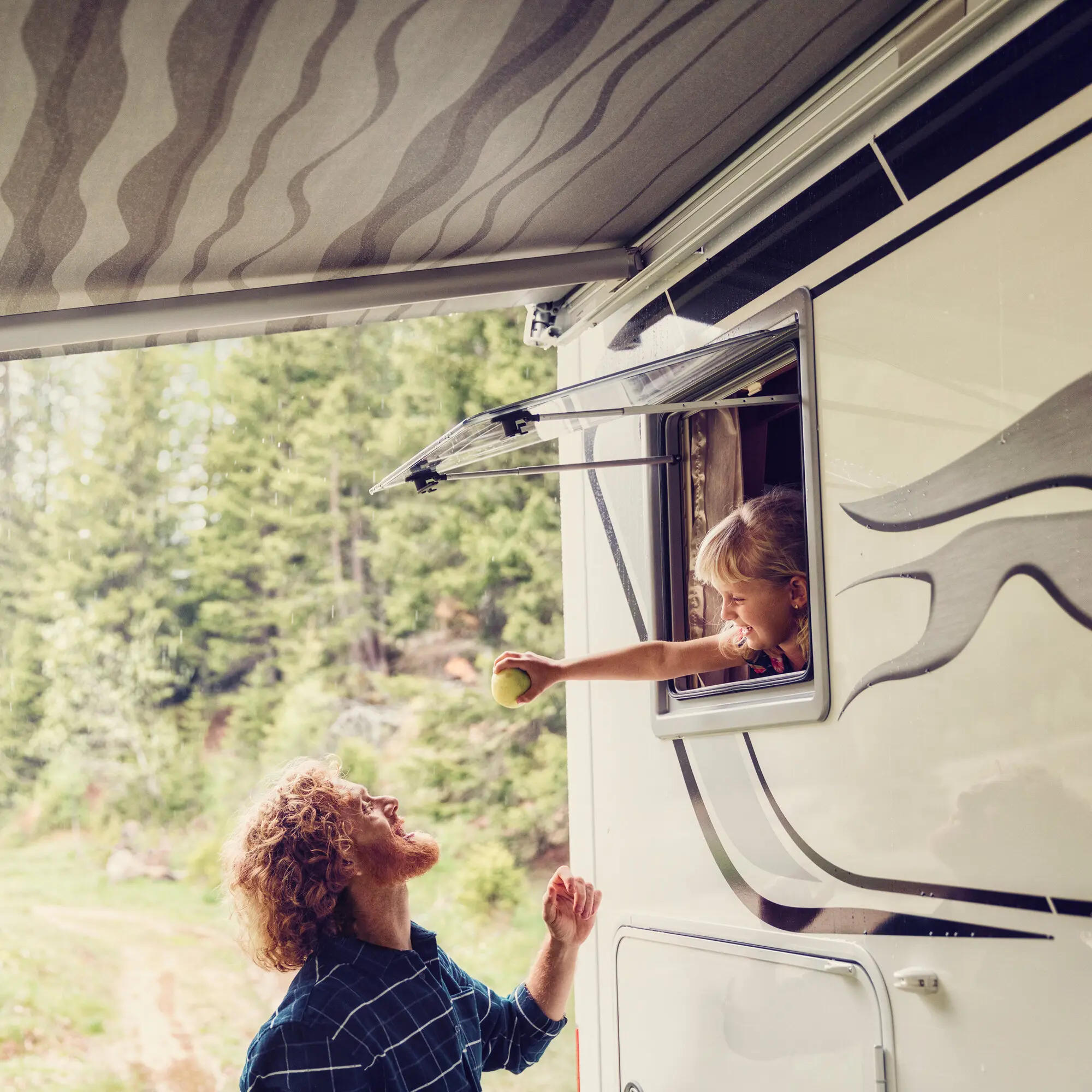 Ausstellfenster S4 am Wohnmobil, geöffnet nach außen; eine Person reicht einen Apfel durchs Fenster, Hintergrund mit Waldlandschaft