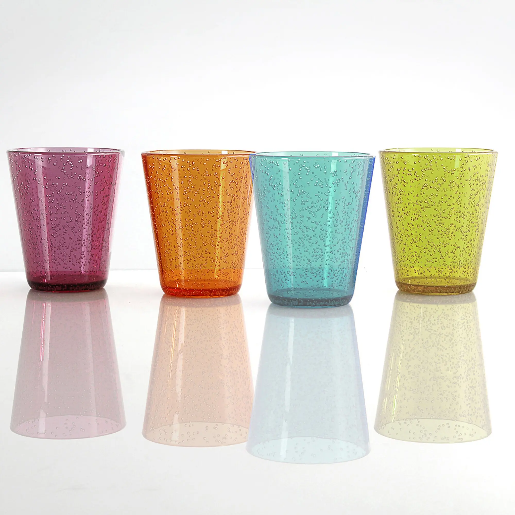 Vier bunte Trinkgläser aus Glas mit vielen Luftblasen in Pink, Orange, Türkis und Gelb stehen nebeneinander auf weißem Hintergrund