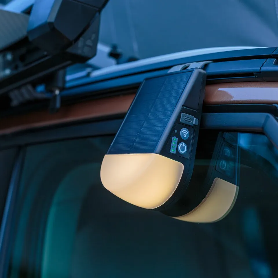 Akku-Outdoor-Solarlampe KL 300 AS mit Solarpanel und Bedientasten, an einem Fahrzeug befestigt und warmweiß leuchtend