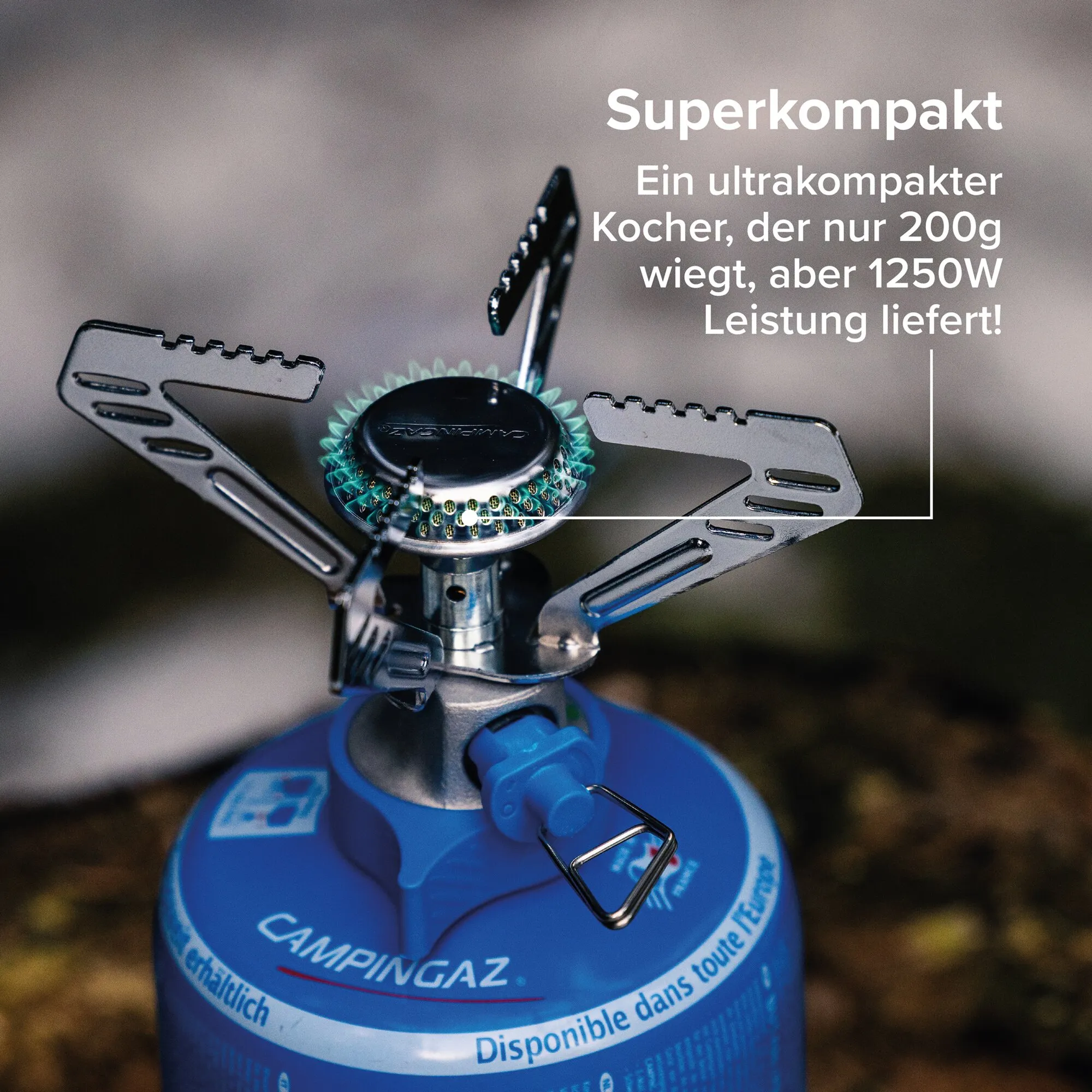 Nahaufnahme eines ultrakompakten Campingkochers mit blauer Campingaz-Gaskartusche, Metallrahmen und sichtbarem Flammenring