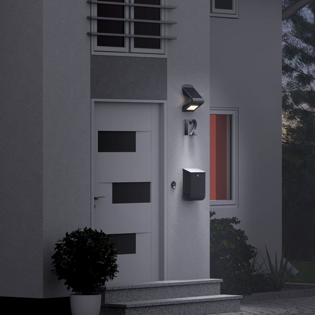 Schwarze LED-Solar-Wandleuchte mit Bewegungsmelder an der Haustür, die Wand über dem Briefkasten nahe der Hausnummer 12 ausleuchtet