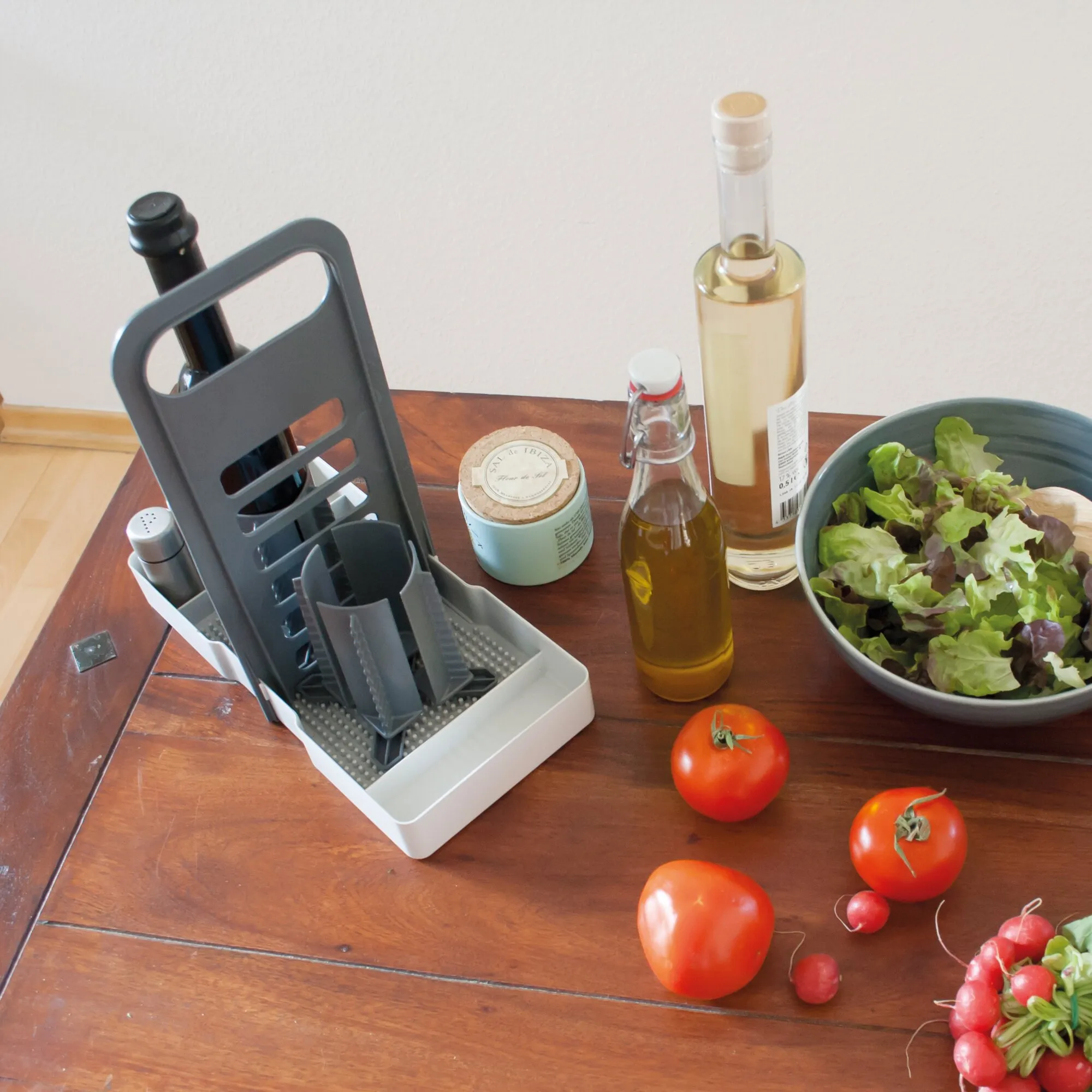 Hellgrauer Flaschenhalter Multi Tray OELE mit mehreren Fächern für Flaschen und Küchenutensilien auf einem Holztisch neben Salat und Gemüse