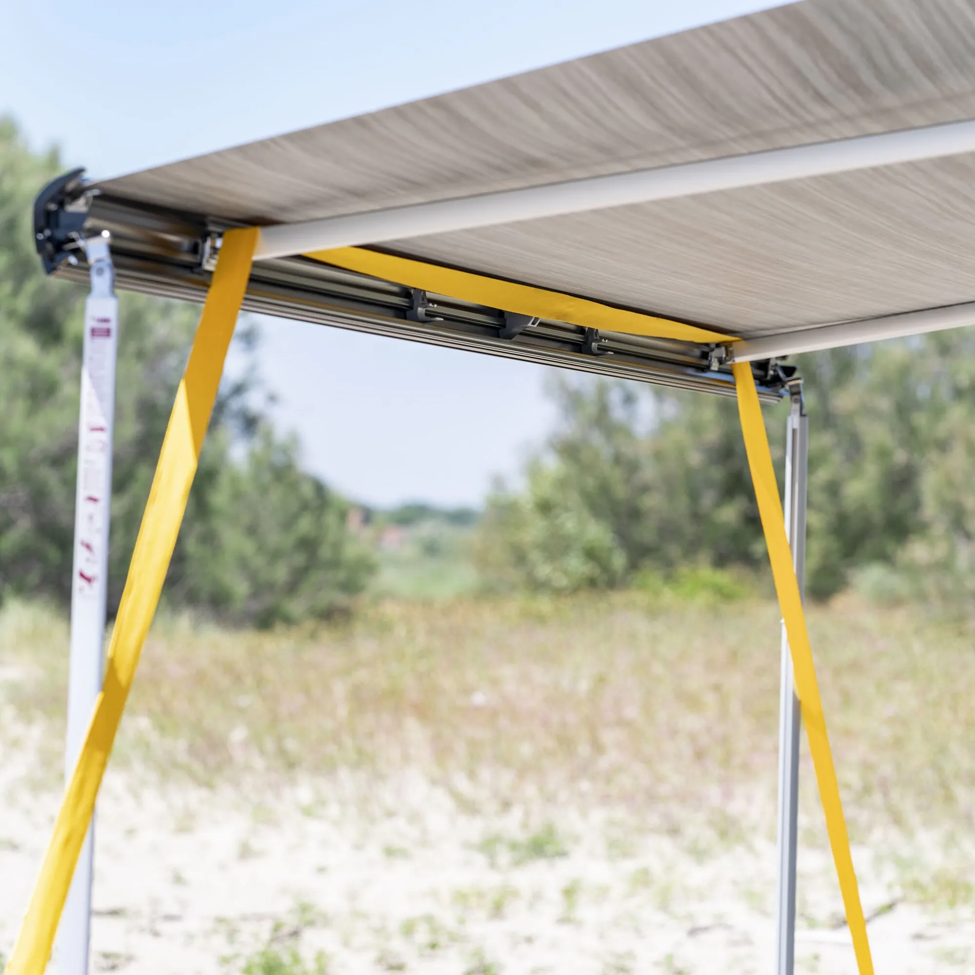 Gelbes Abspannband Tie Down an der Unterseite einer befestigten Markise mit Metallgestänge im Außenbereich