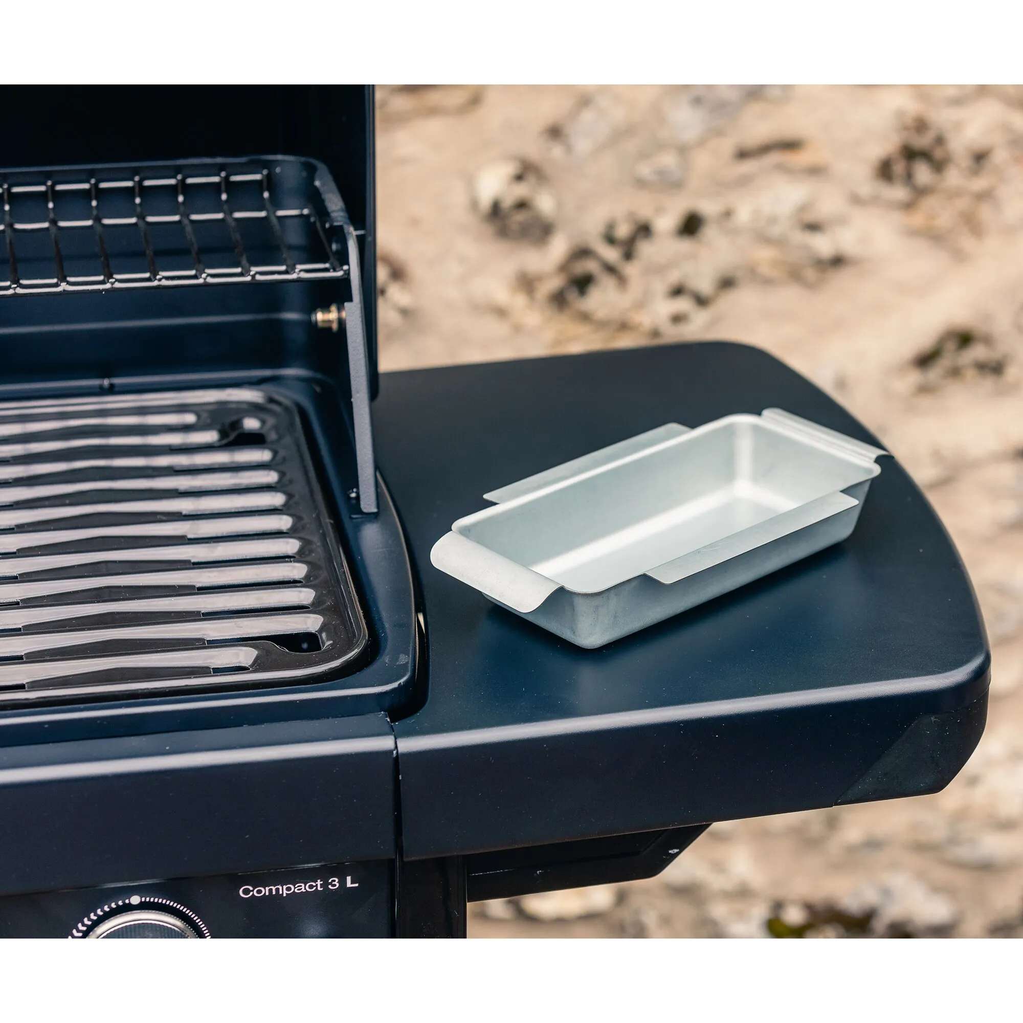 Geöffneter schwarzer Gasgrill Compact 3 L mit Grillrost und herausnehmbarer Metallschale auf der Seitenablage