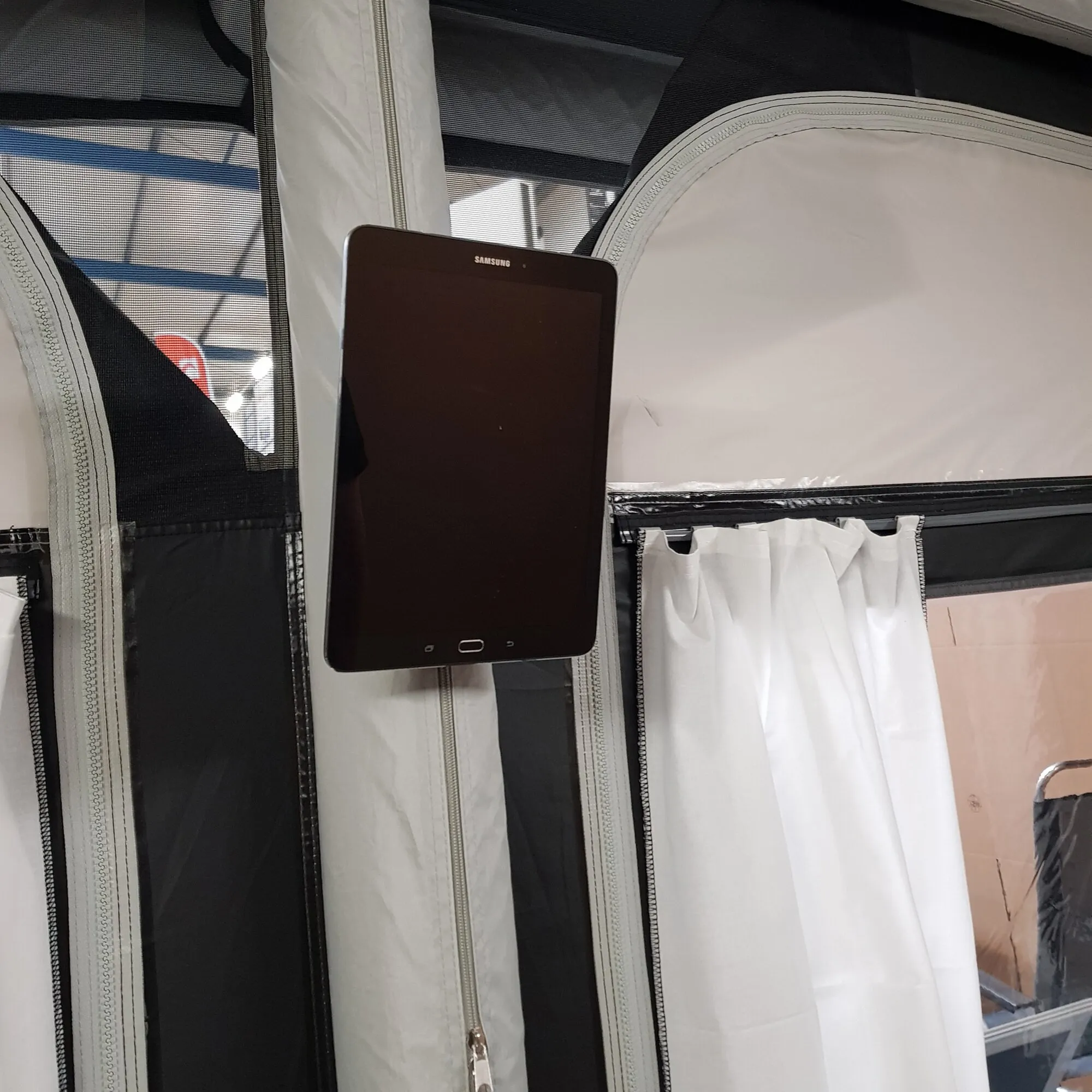Schwarzes Samsung-Tablet in Hochformat, befestigt an einer weiß-schwarzen textilen Fläche mit Reißverschlüssen