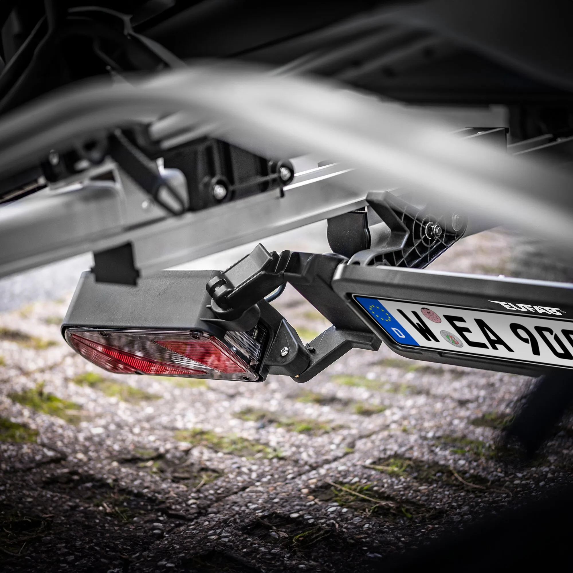 Detailaufnahme des silbernen Fahrradträgers SD260 an der Anhängerkupplung mit Rückleuchte und Kennzeichenhalterung