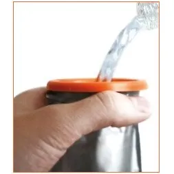 Taschen-WC roadbag® mit orangefarbenem Rand, das eine Hand hält, während Flüssigkeit durch die Öffnung in den silbernen Beutel läuft