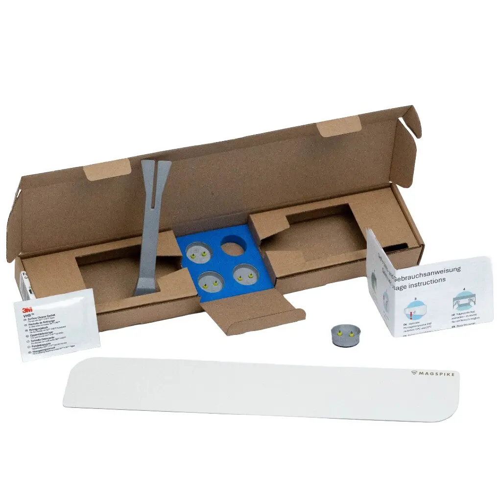 Weißes Trägerplatten-Panel des MagSpike Set L ohne Haken, im geöffneten Karton liegend, blaue Innenverkleidung, drei runde Magnete und Anleitung sichtbar